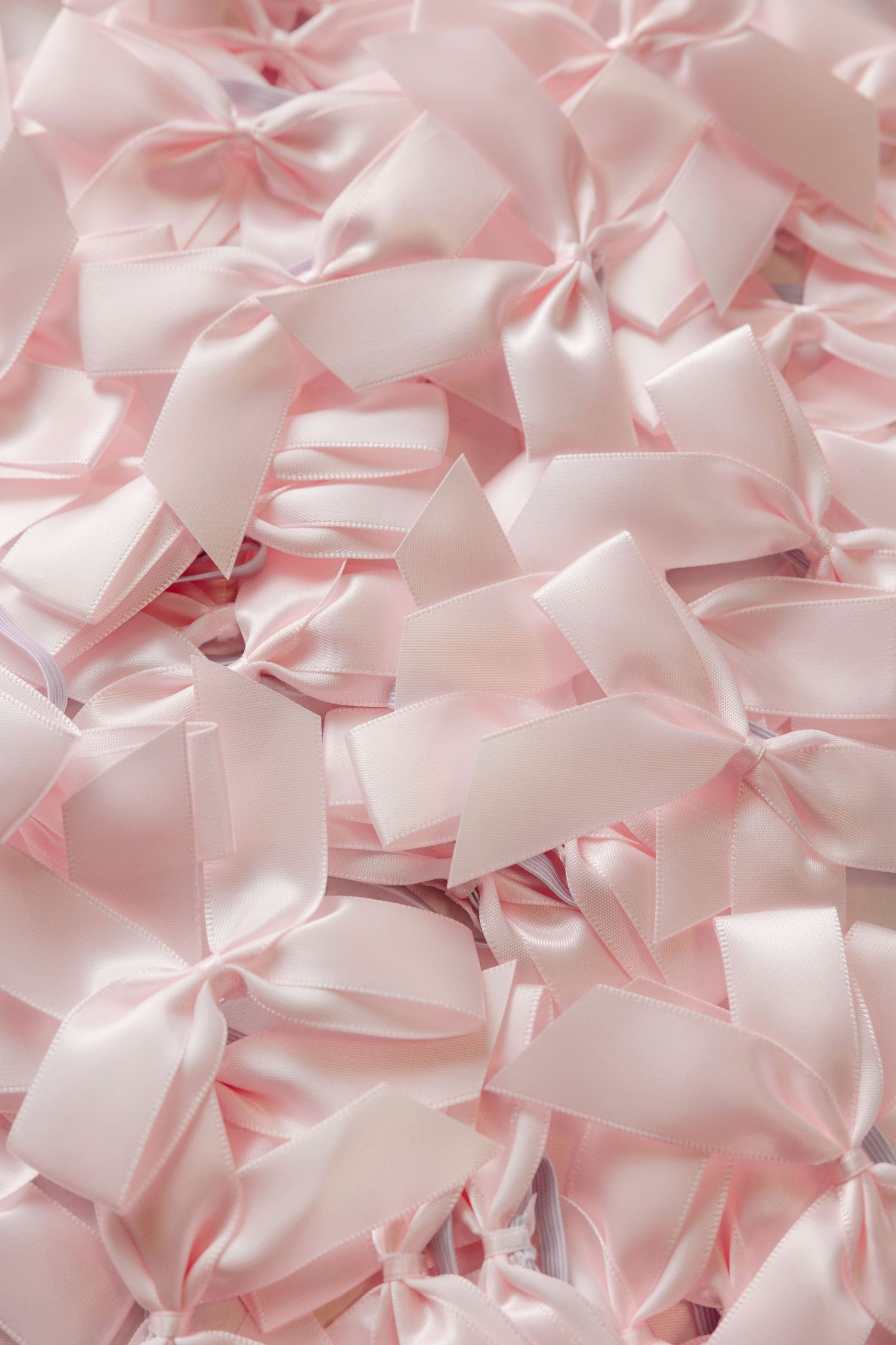 Delicate pink satin bows arranged in a repeating pattern background.