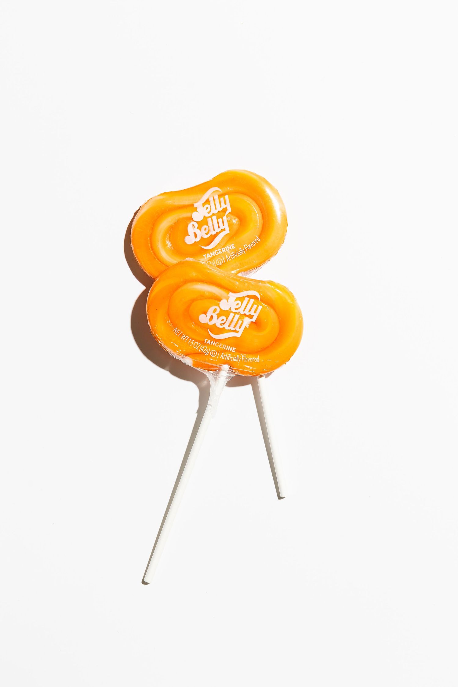 Orange Jelly Belly candies on white sticks against white background.