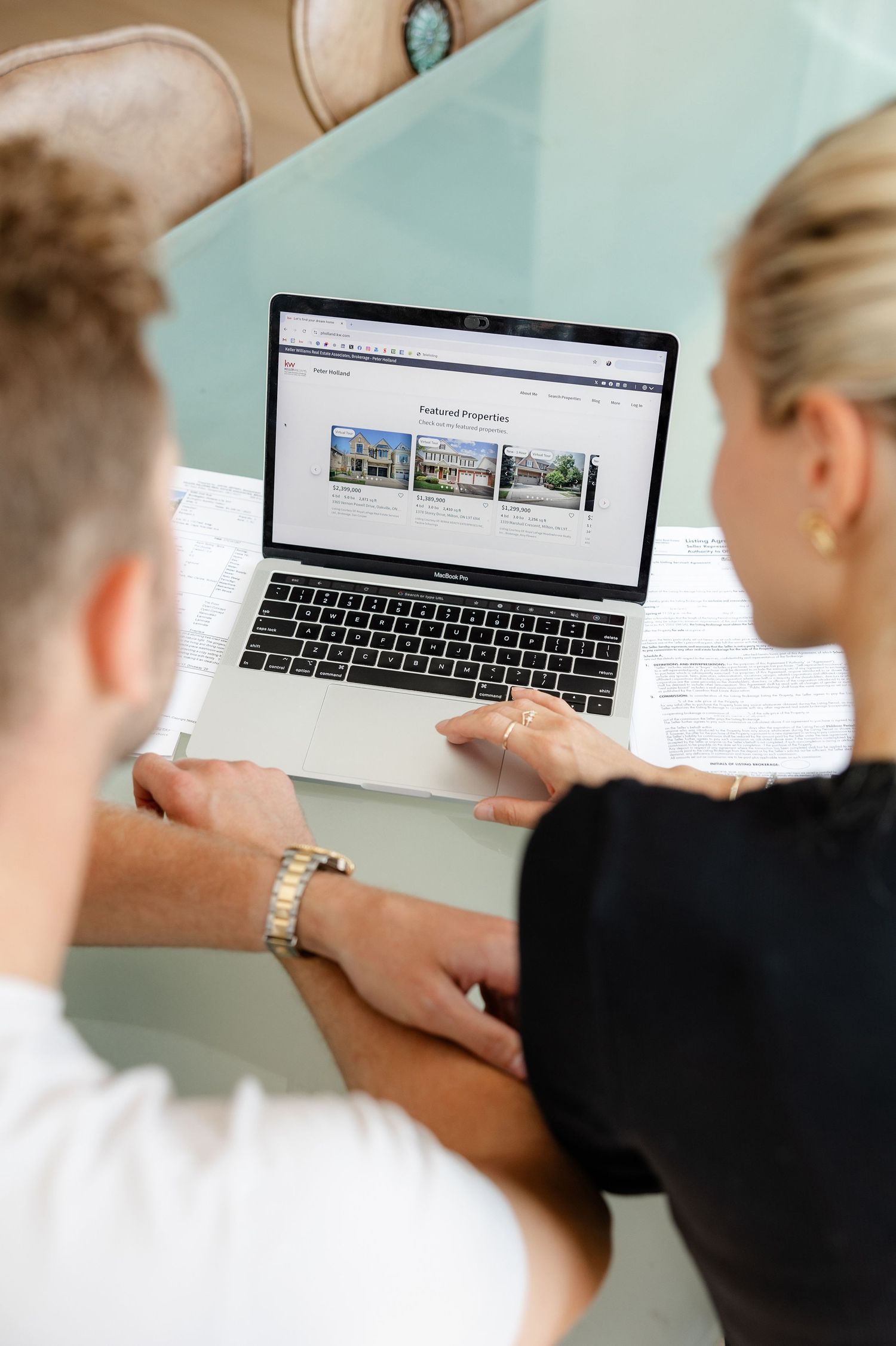 Two people looking at real estate listings on a laptop screen together.