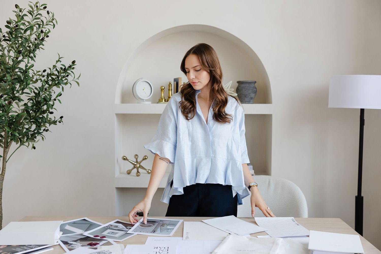 Professional working at desk with papers and documents beneath arched wall shelving.