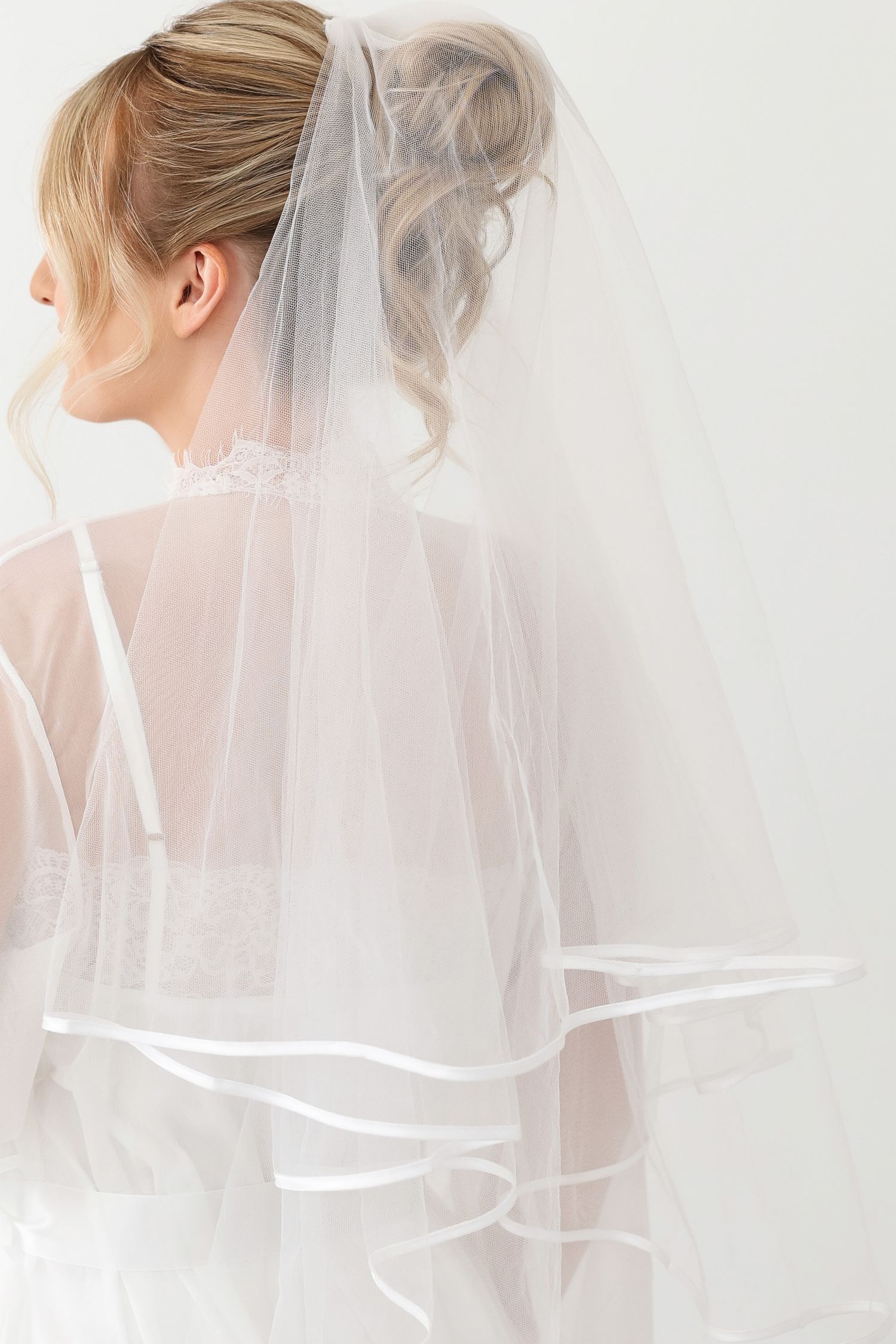 Ethereal sheer wedding veil photographed from behind showing flowing fabric movement.