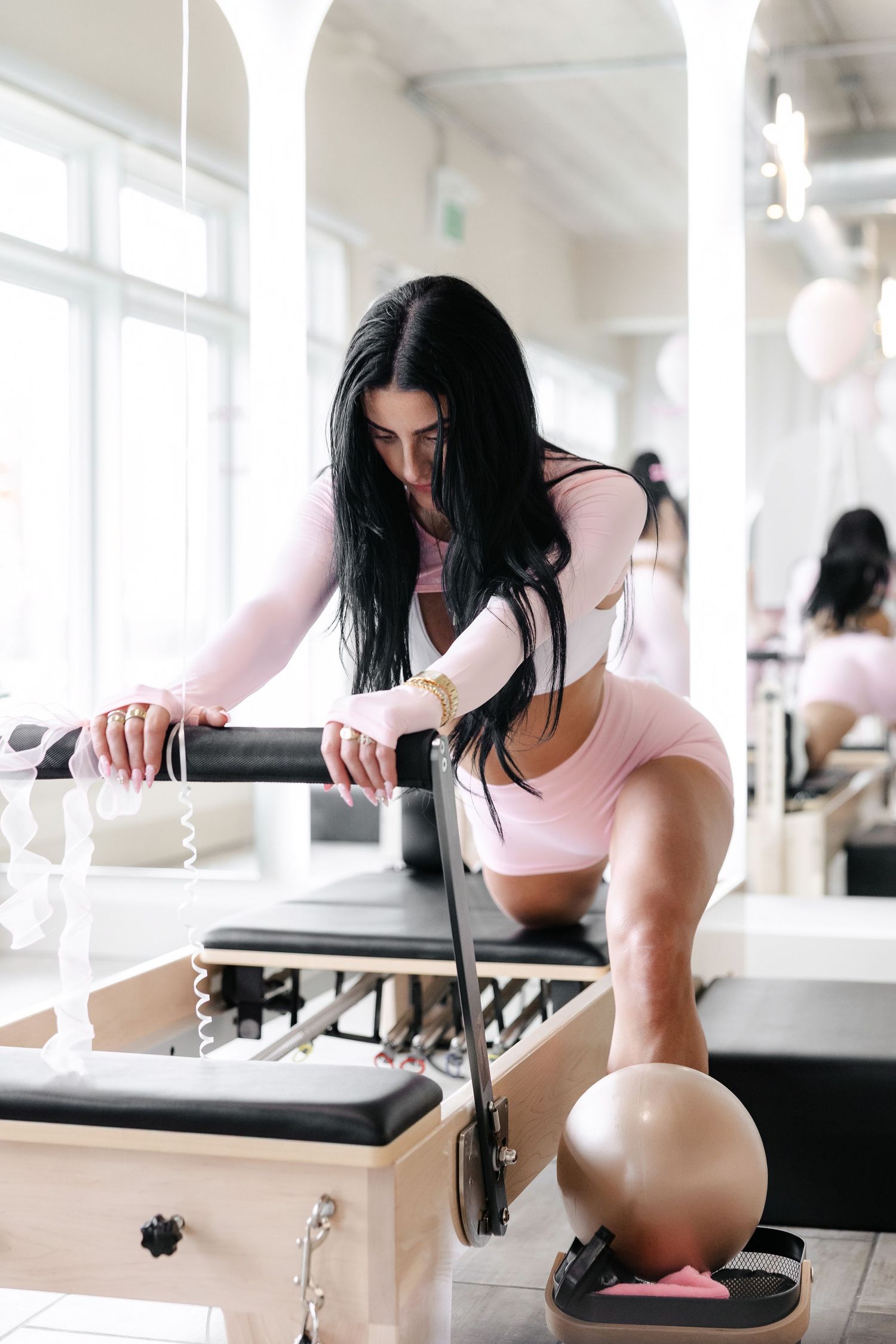 Modern fitness studio with pilates reformer machines and white balloon decorations.