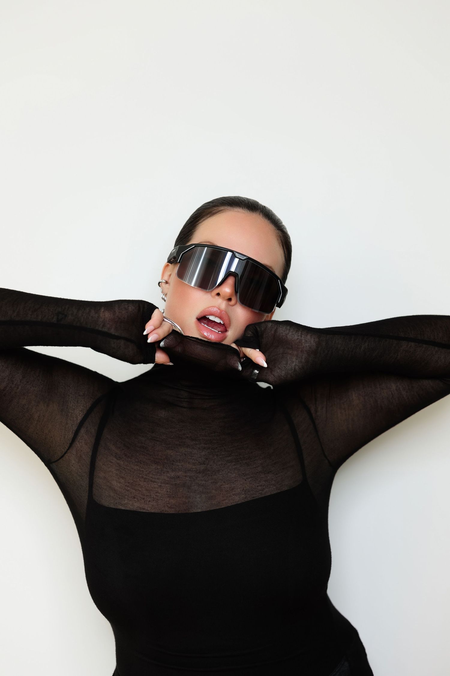 Dramatic fashion series in black outfit with sunglasses against white background.