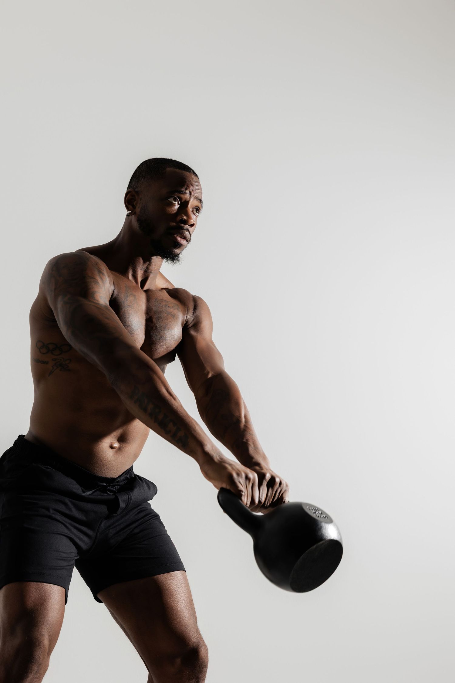 Athletic figure performing kettlebell exercise against white background.
