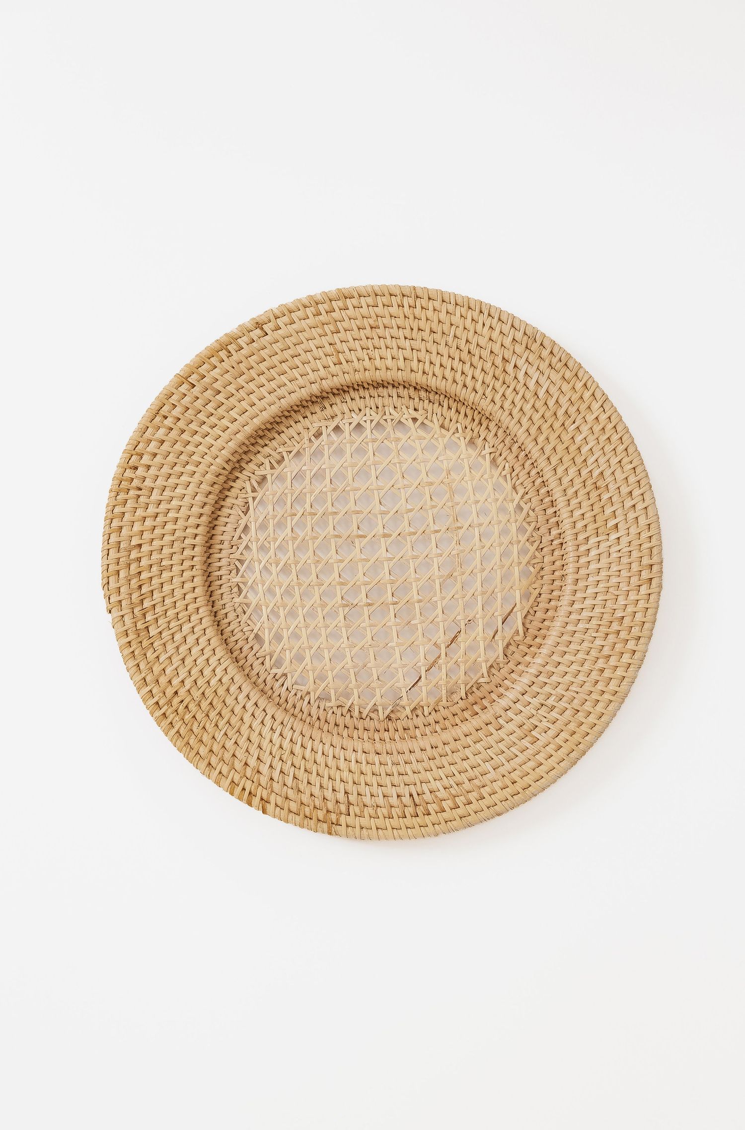 Round woven rattan charger plate in natural beige color.