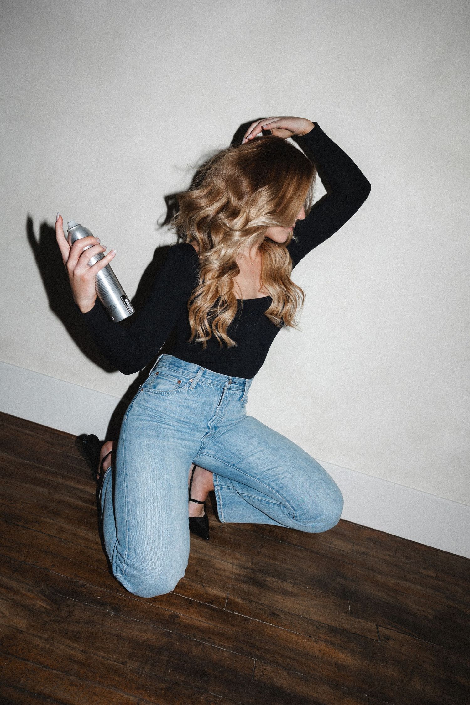 Dynamic fashion pose showing movement in denim and black outfit.