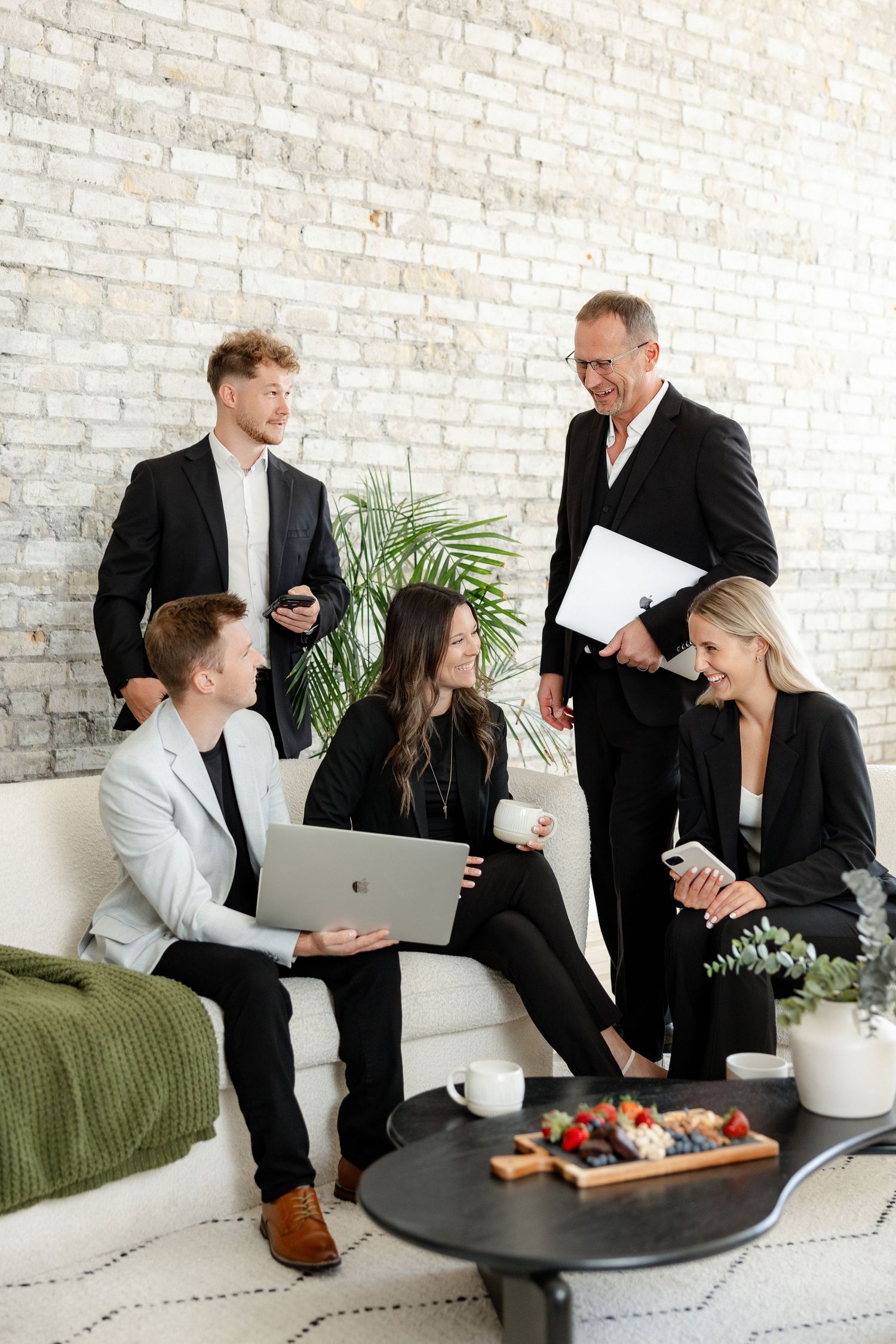 Business team collaborates in modern office space with white brick wall and green couch.