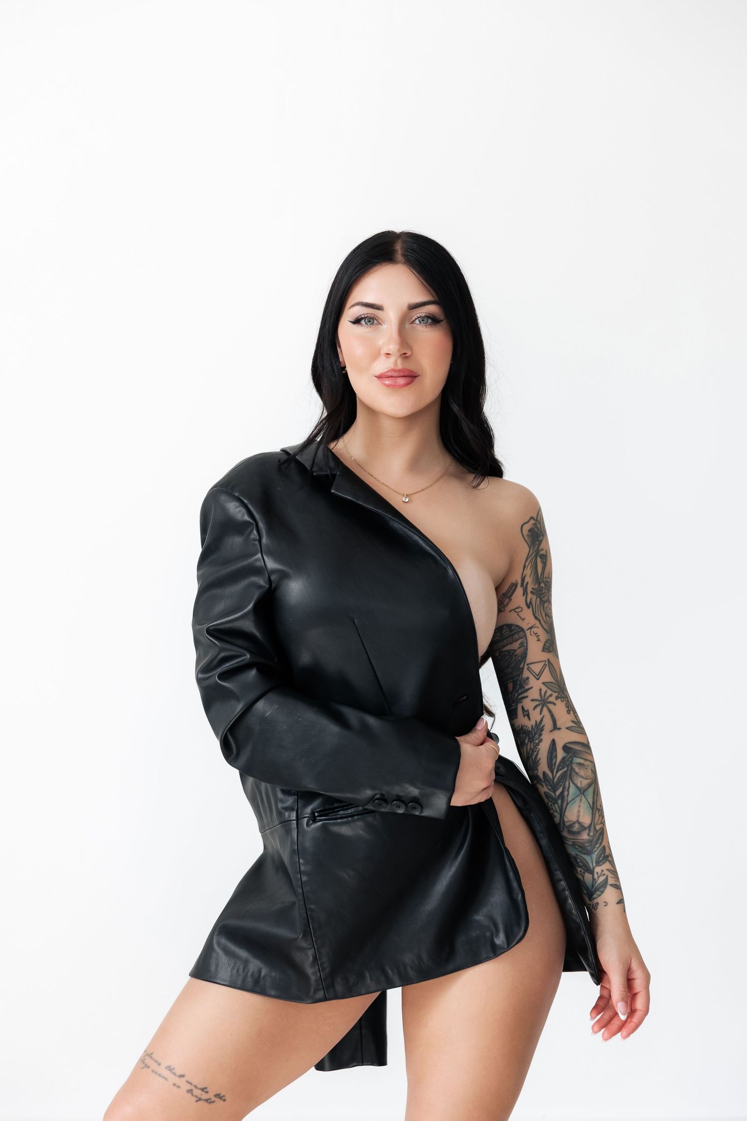 Model in black leather jacket poses confidently against white background.