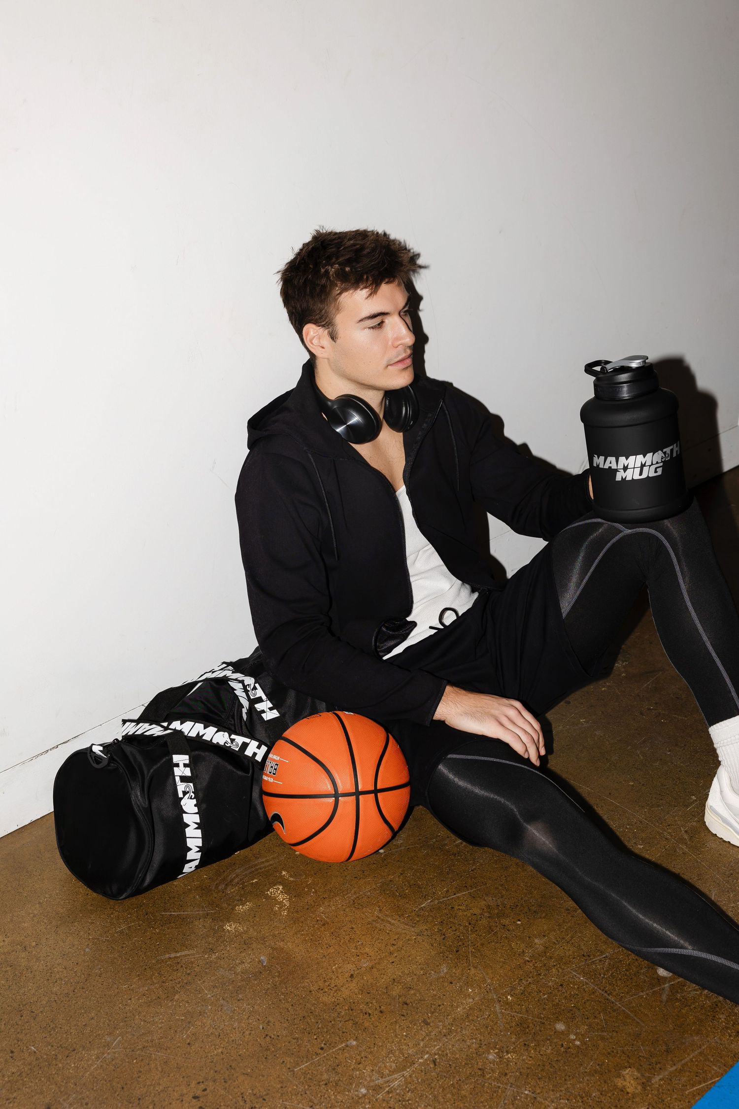 Person lounges on floor with basketball wearing all black athletic wear.