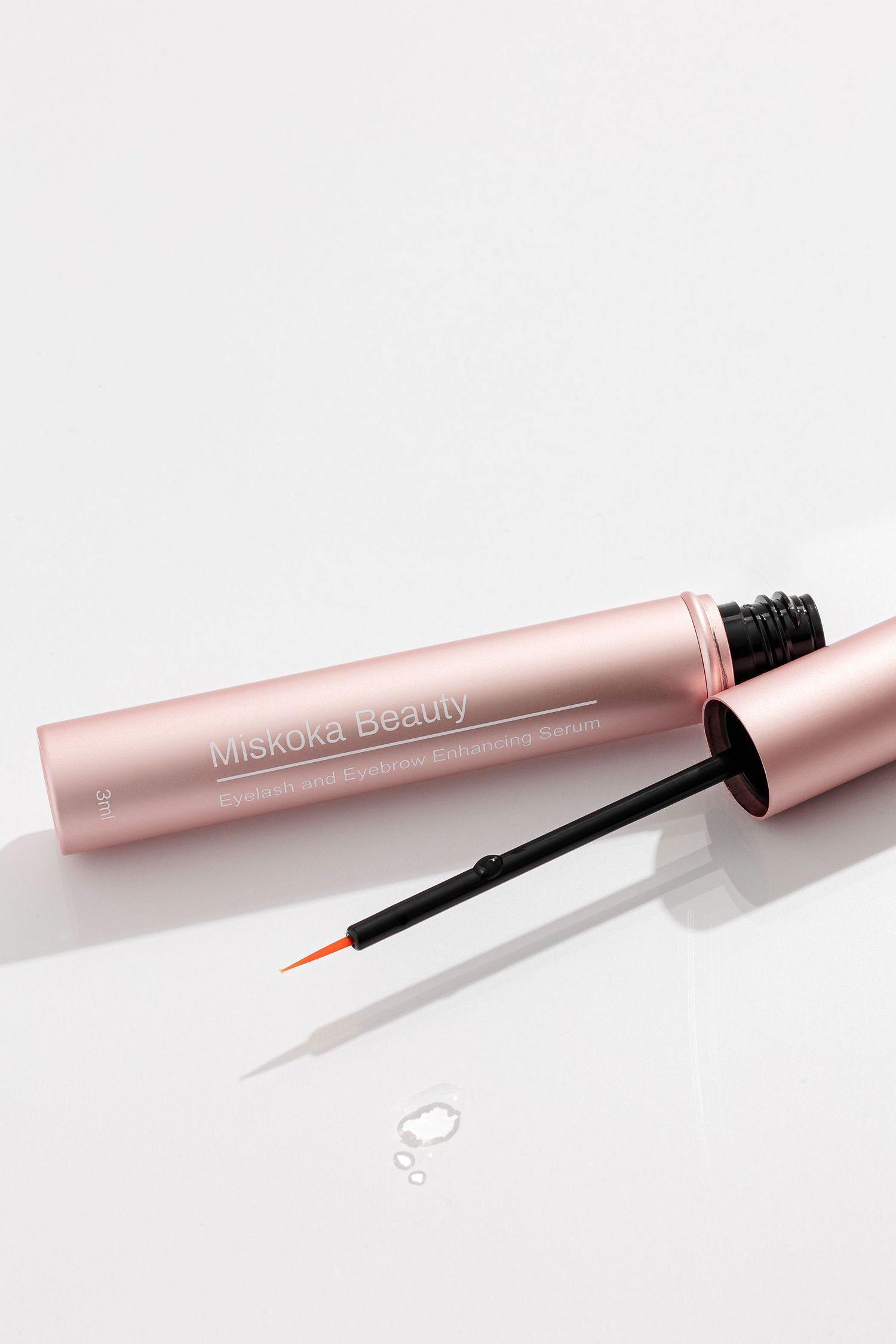 Rose gold liquid eyeliner tube with fine brush applicator on white surface.