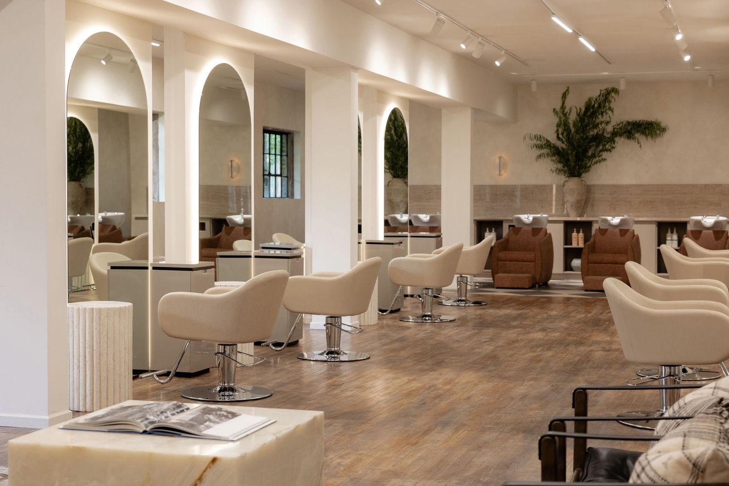 Minimalist white salon space with elegant arched columns and styling stations.