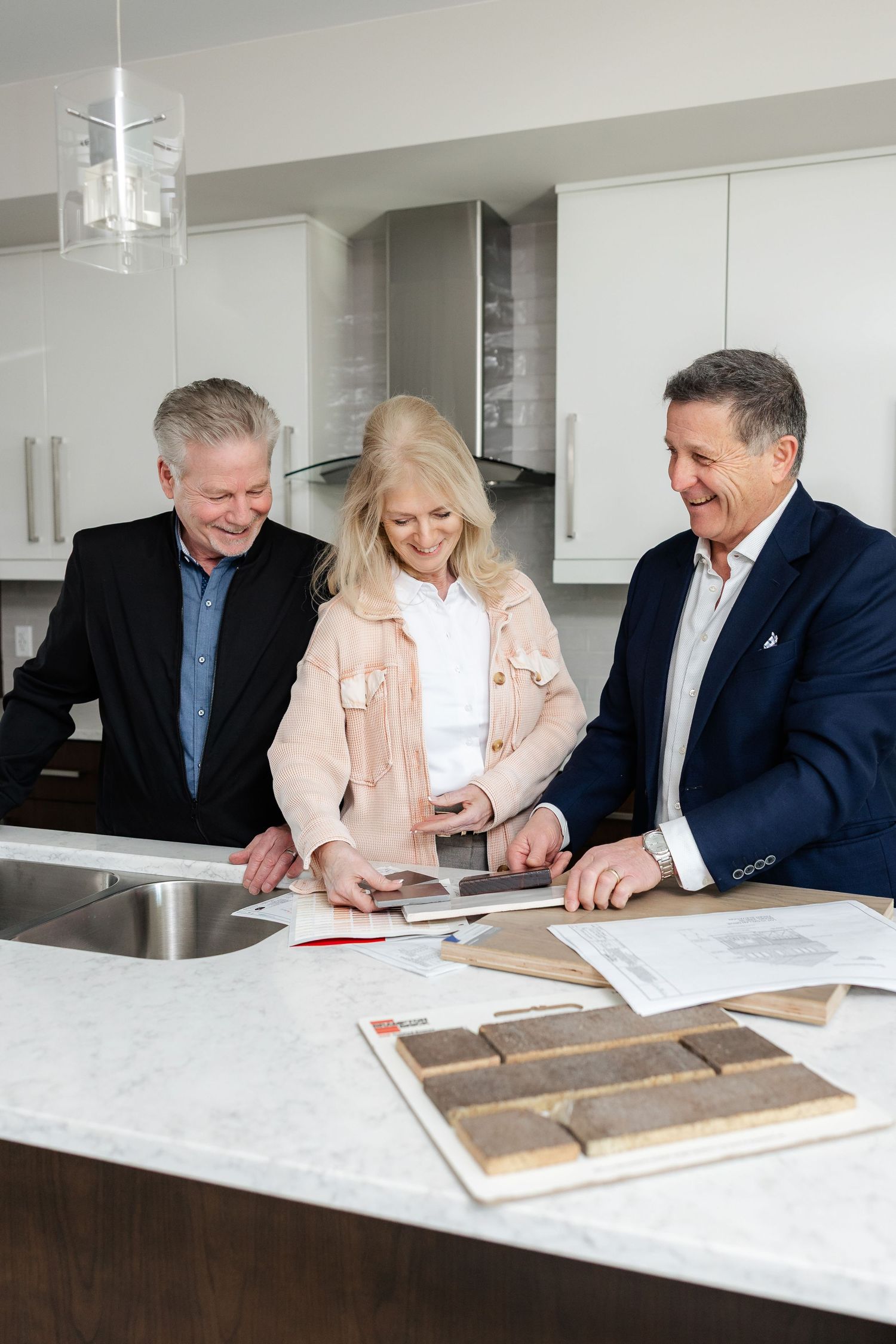Team reviewing renovation samples and documents together in bright kitchen setting.