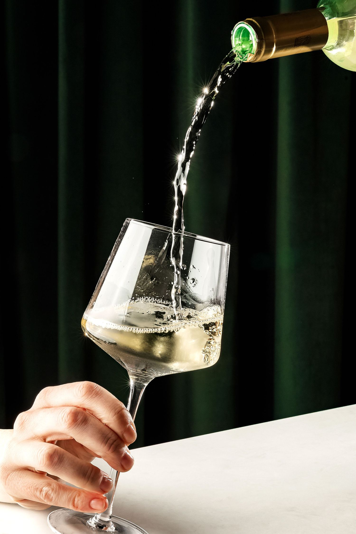 Champagne being poured into an angled glass against dark background.