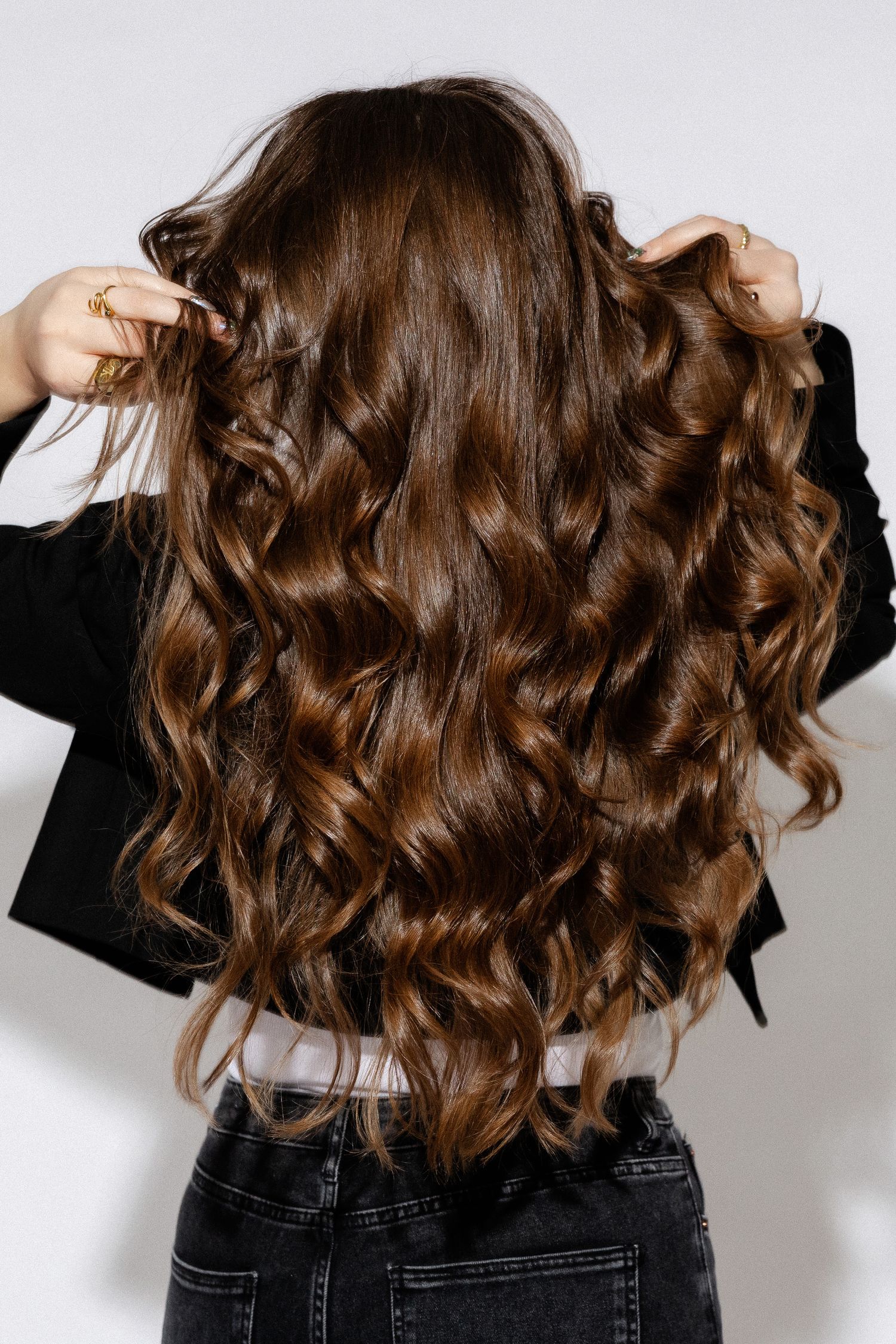 Back view of wavy brown hair styled in loose curls against white background.