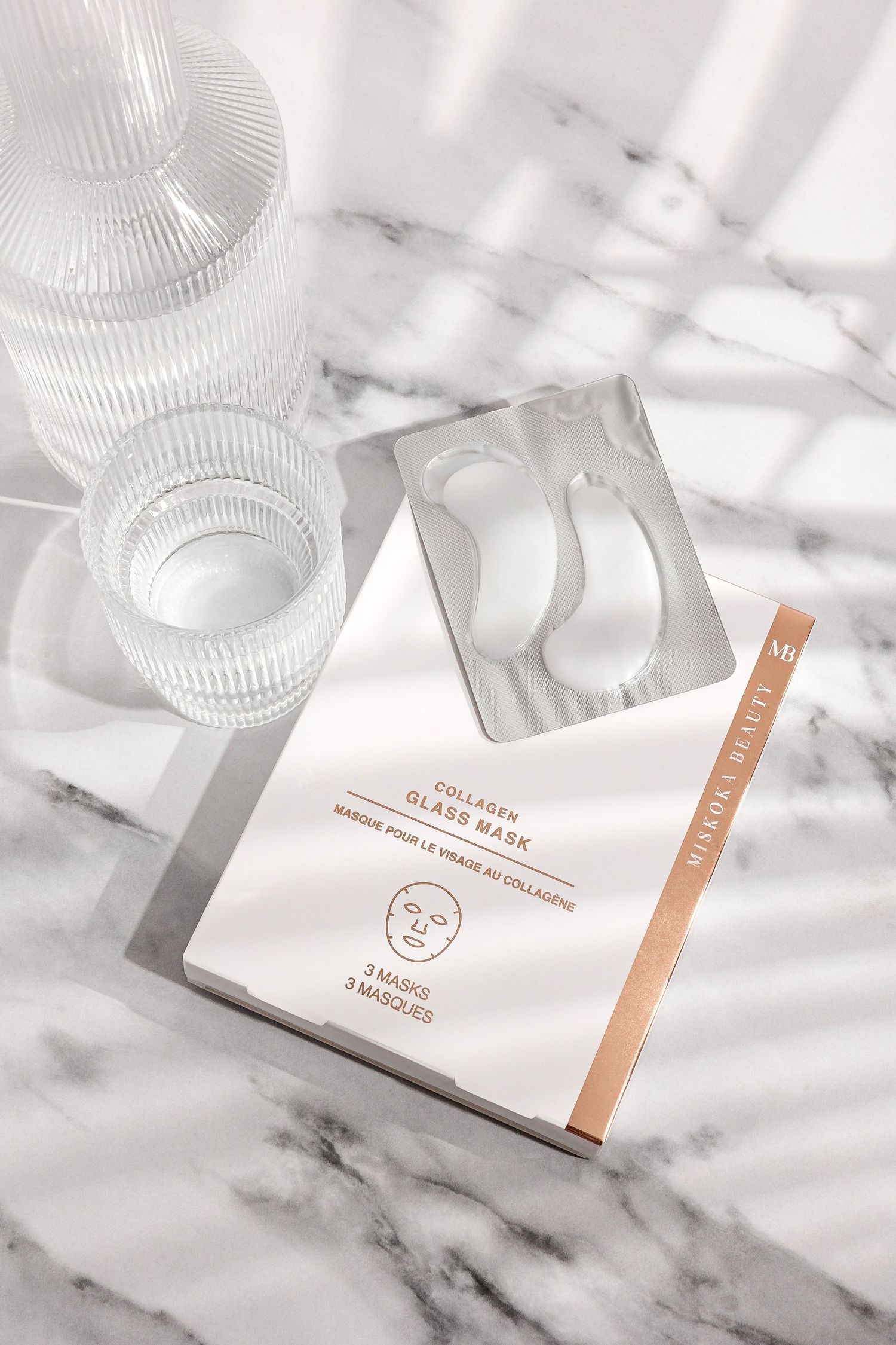 White beauty product packaging with copper accents photographed on marble surface.