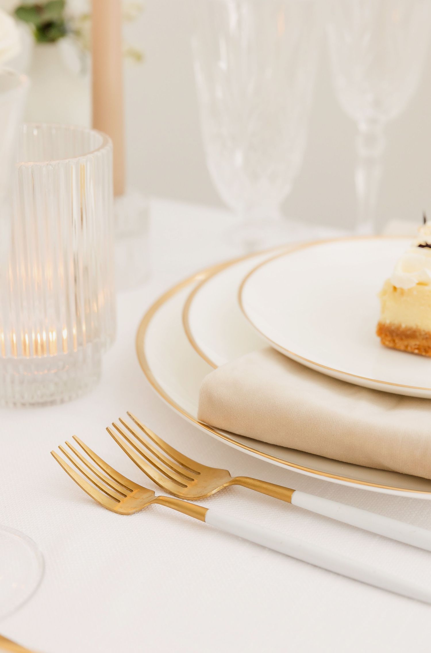 Modern table setting with gold flatware and white plates featuring delicate gold rim details.