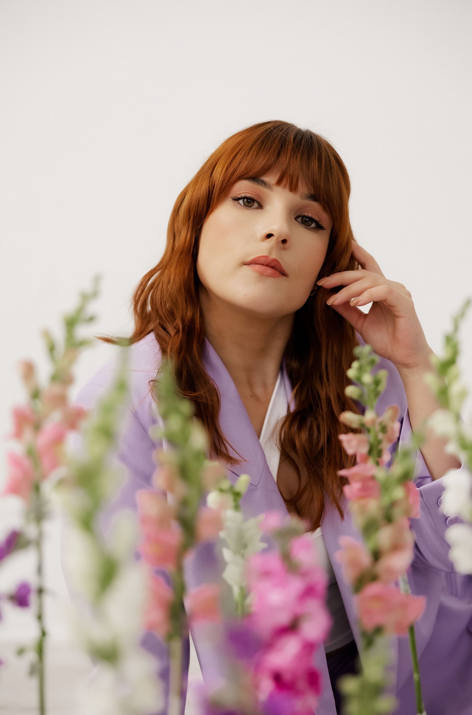 Ethereal portrait composition with pink and purple flowers creating soft focus effect.