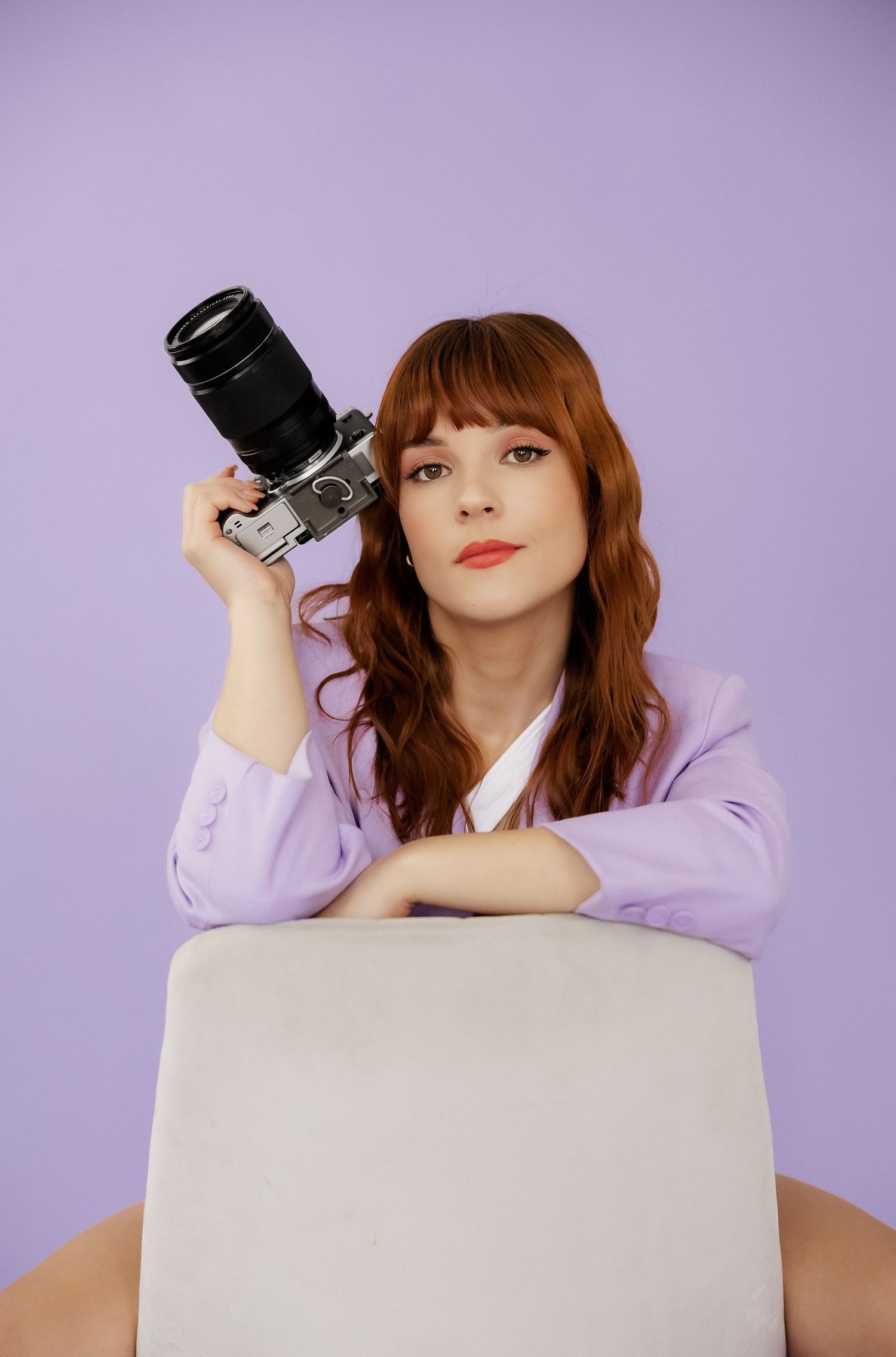 Creative poses with professional camera on white platform against purple background.