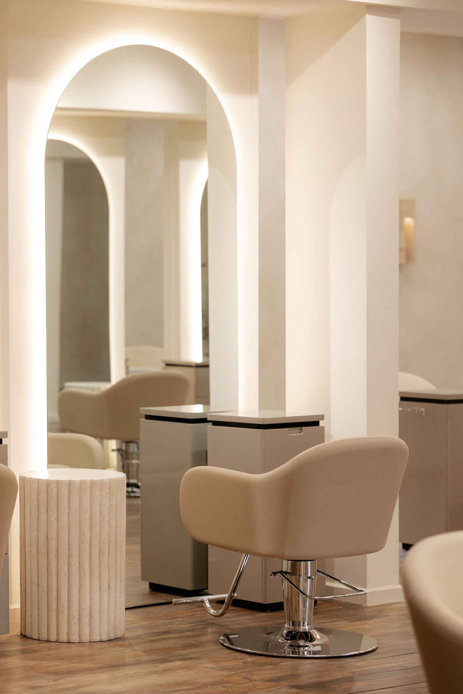 Modern hair salon interior with sleek white arches and comfortable styling chairs in minimalist design.