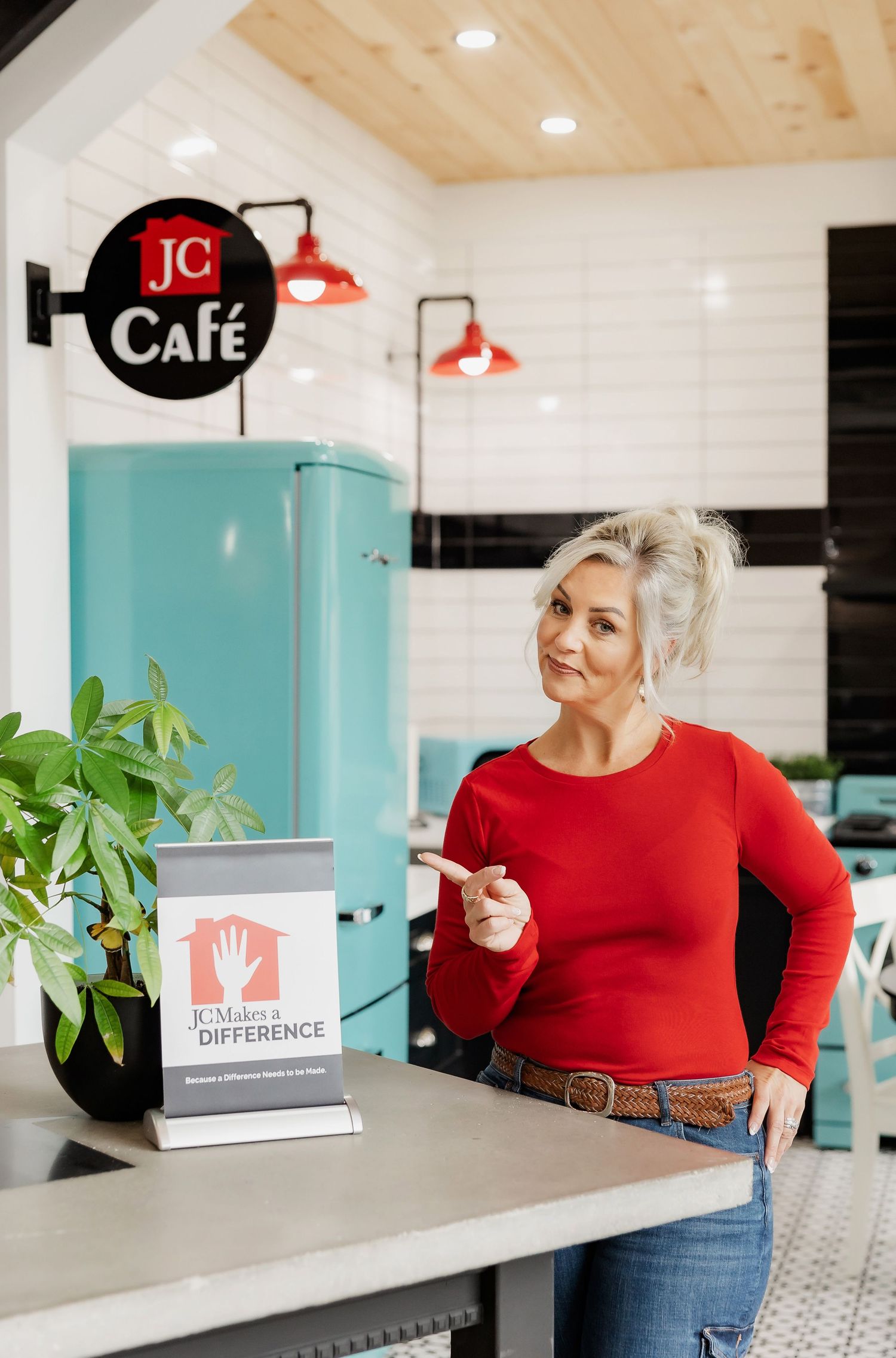 Modern cafe interior with turquoise retro fridge and red industrial lighting fixtures.