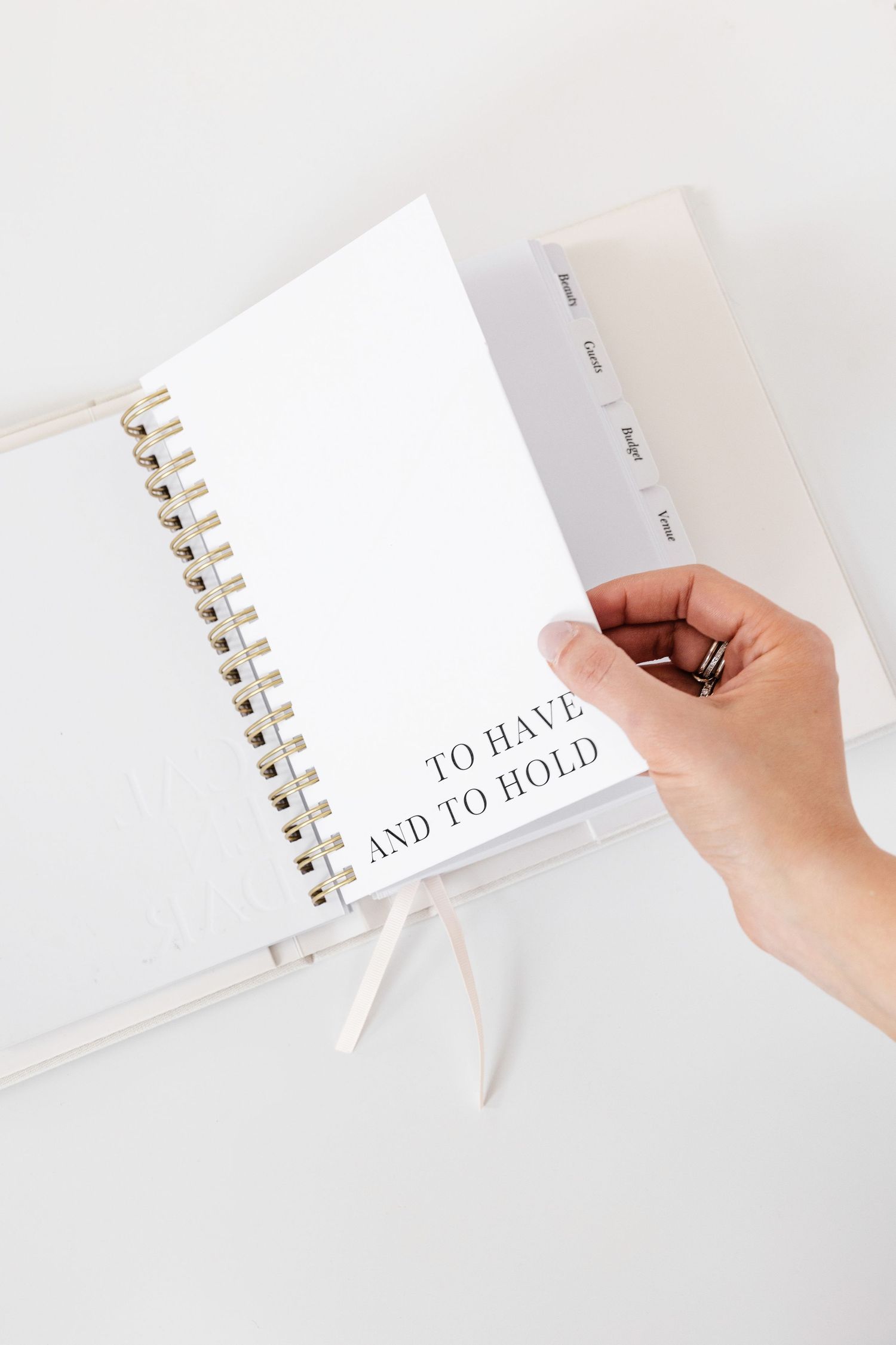 Hand flipping through pages of a white spiral notebook with gold binding.