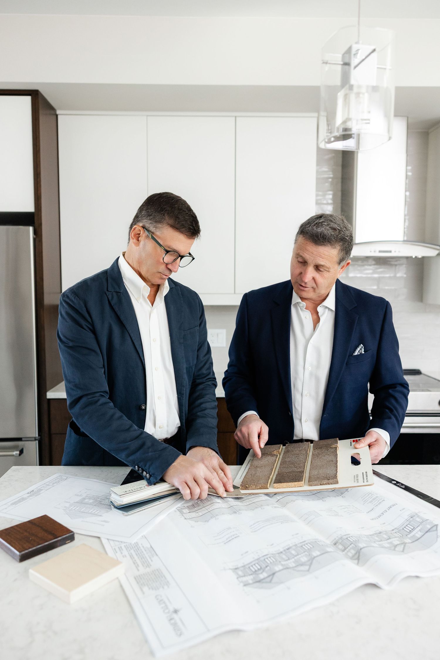 Business professionals reviewing architectural plans and documents on white table.