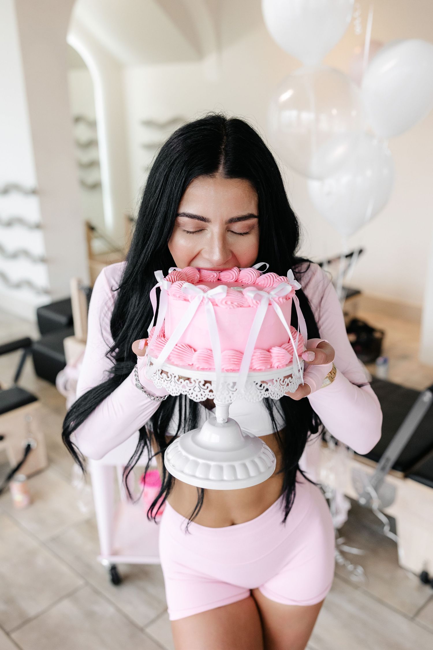 Pink birthday cake being held during fitness studio celebration.