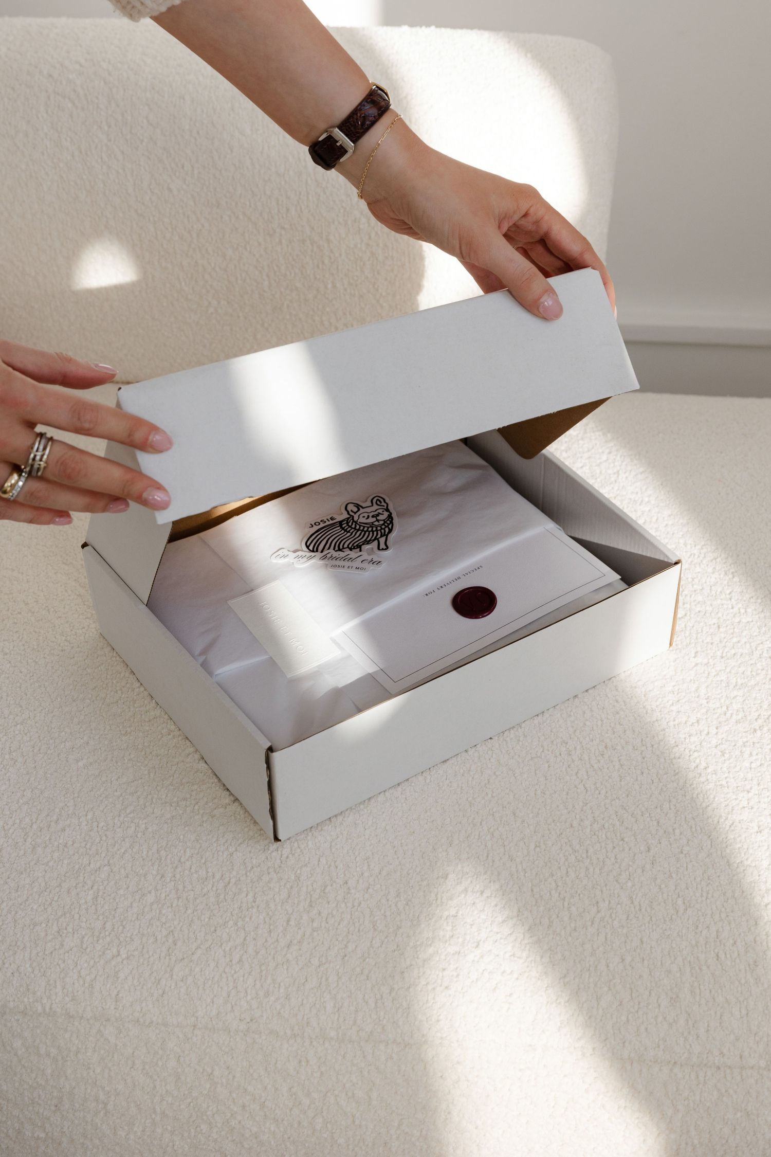 Hands opening a white branded box with red wax seal.