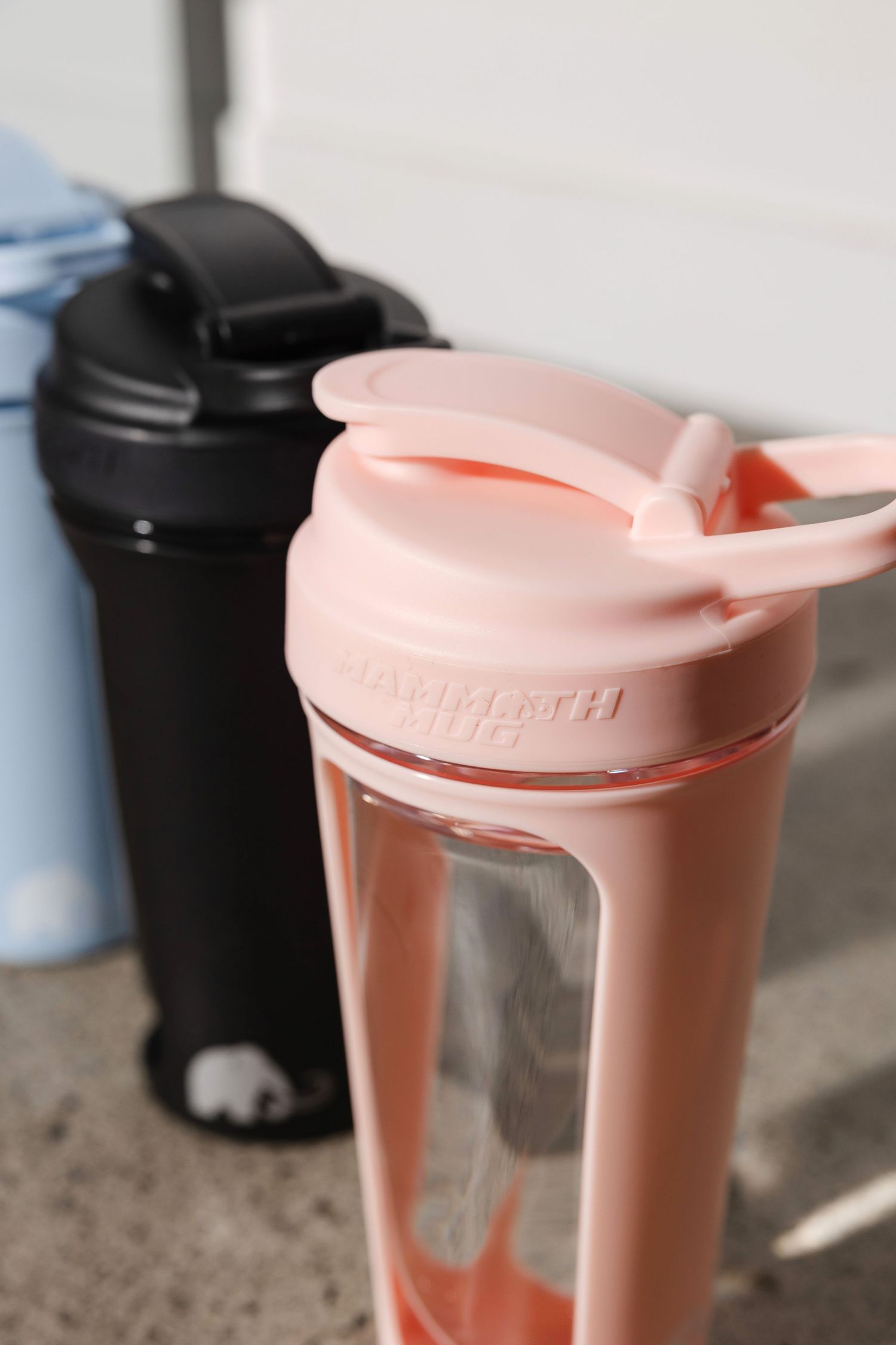 Pink and black reusable water bottles lined up on a surface showing different lid designs.