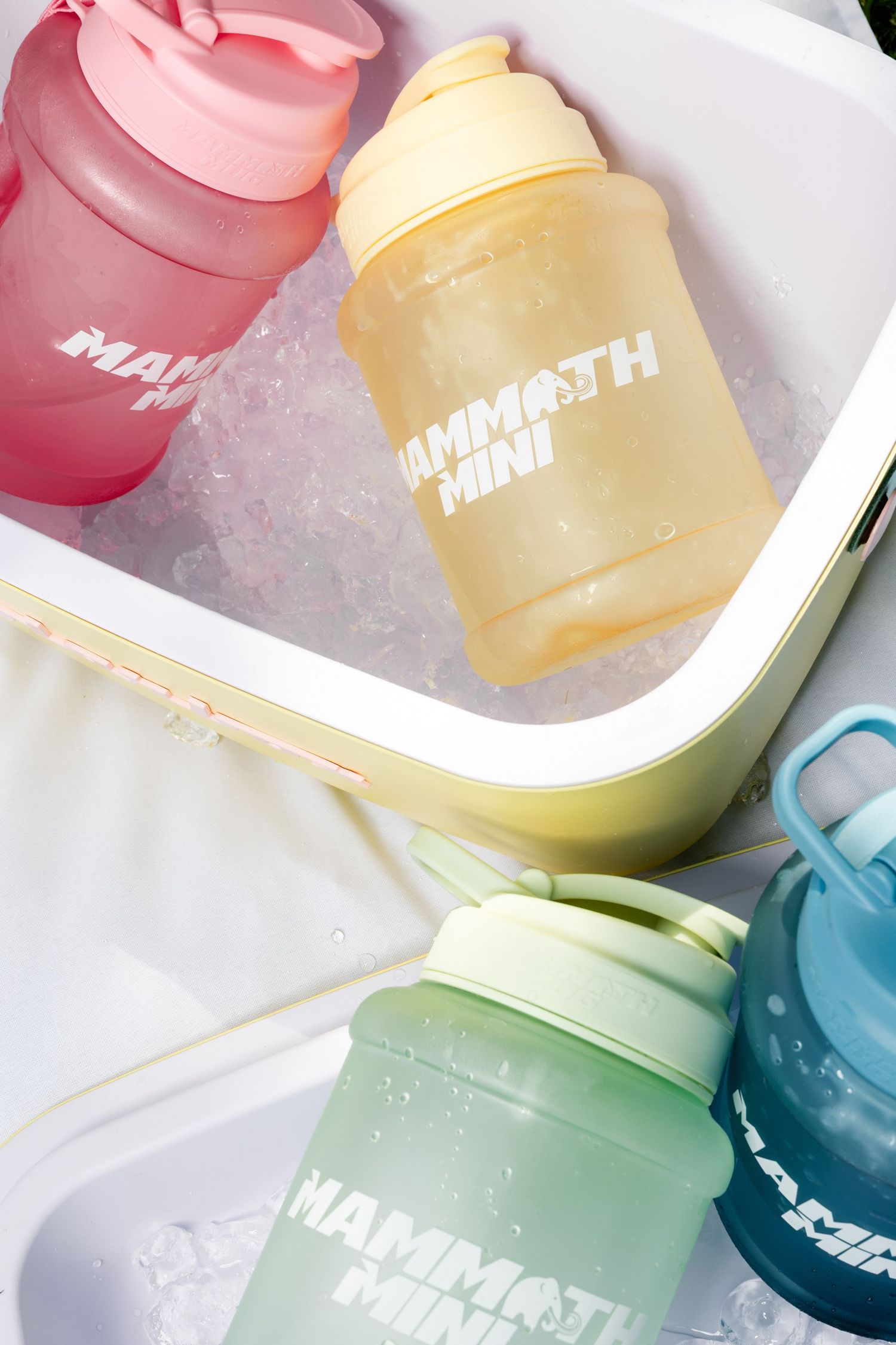 Colorful water bottles in pastel shades displayed on ice in cooler.
