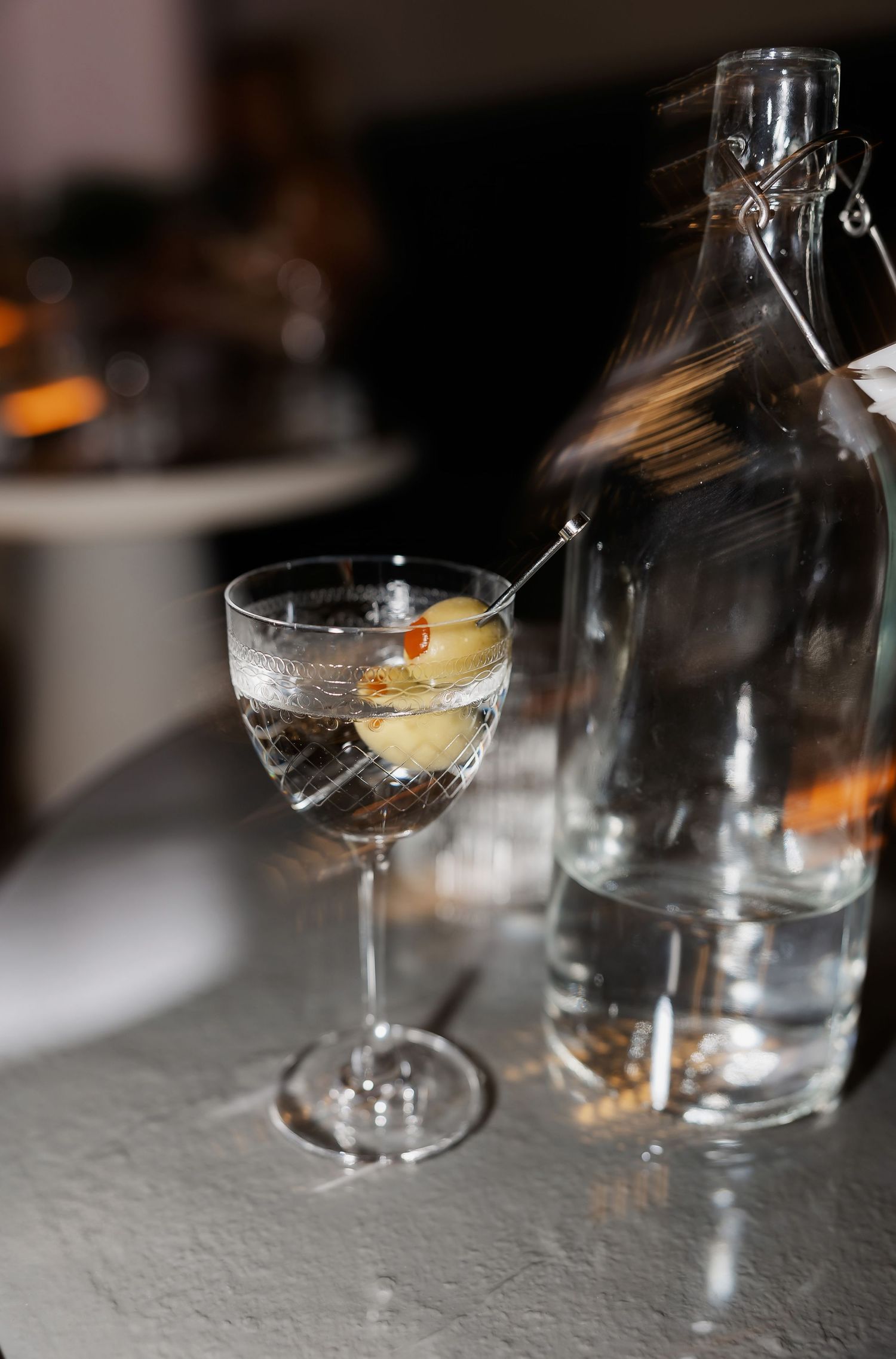 Close-up of elegant cocktail glasses and bottles arranged on a textured surface.