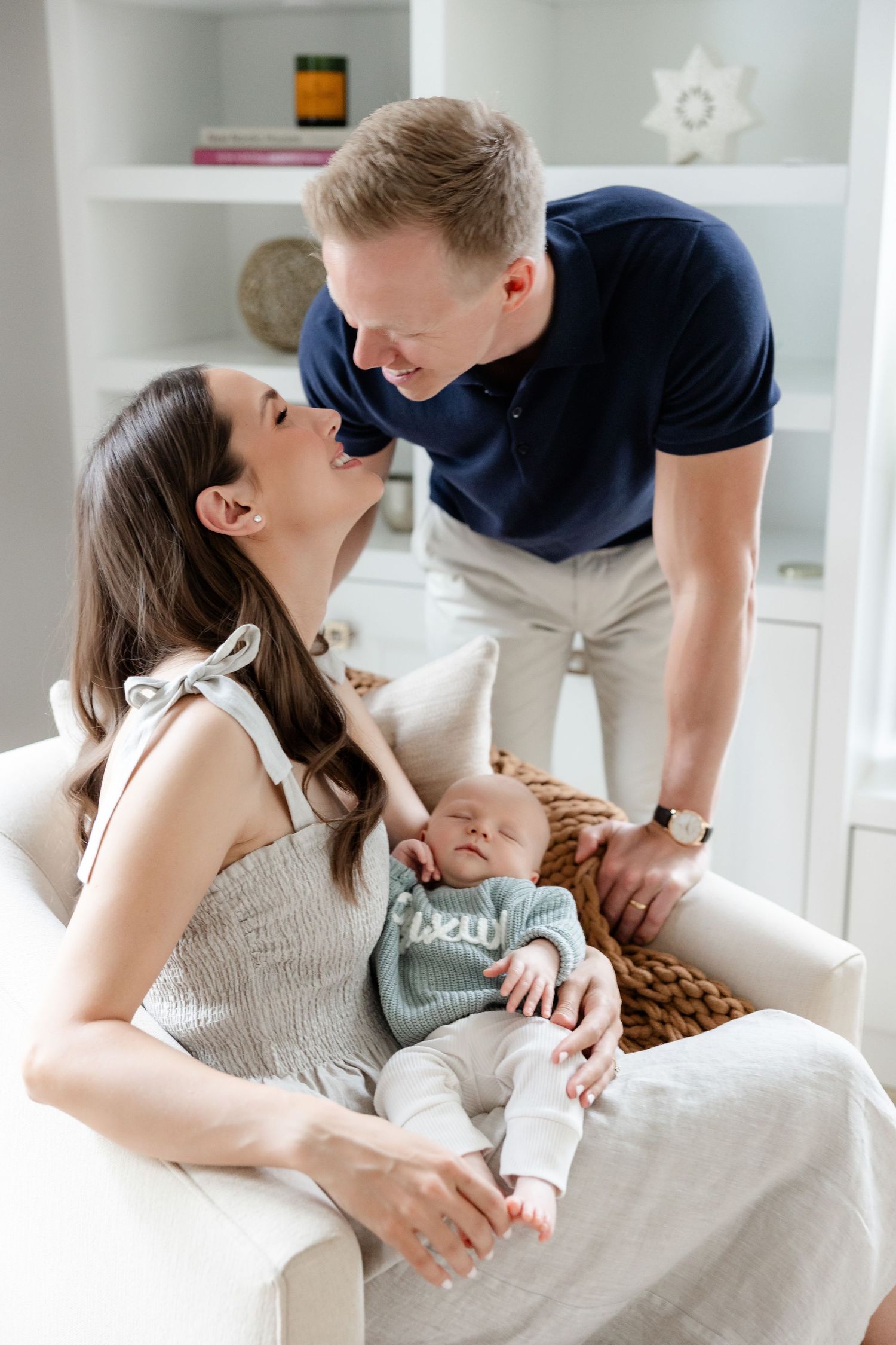 Intimate family moment in bright modern nursery with white built-in shelving.