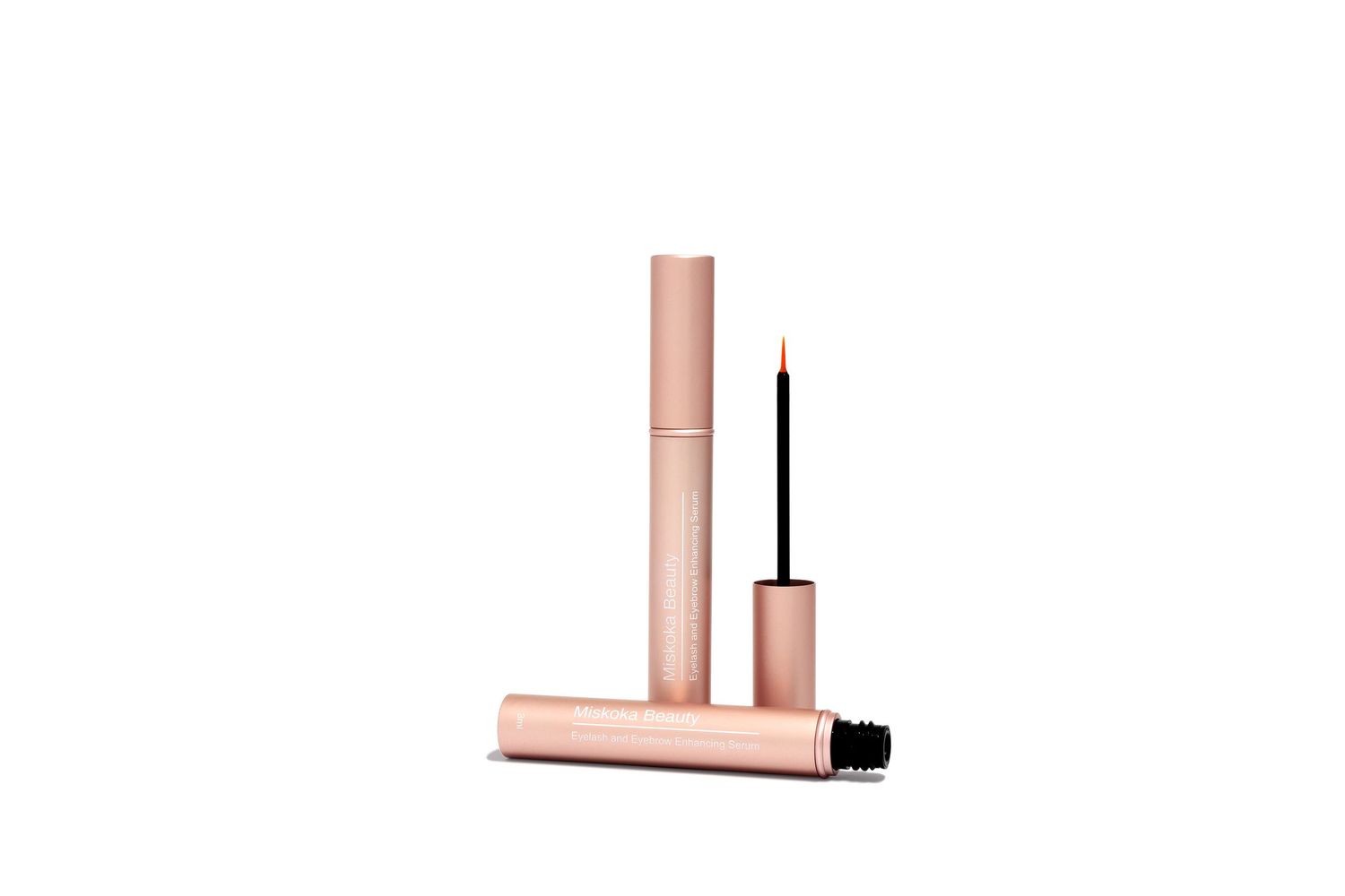 Rose gold mascara or eyeliner tubes with black applicator brush against white background.