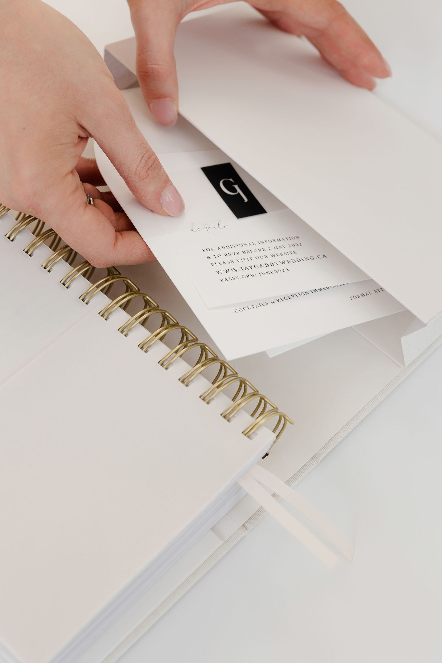 Hands flipping through pages of a white spiral-bound planner with gold binding.