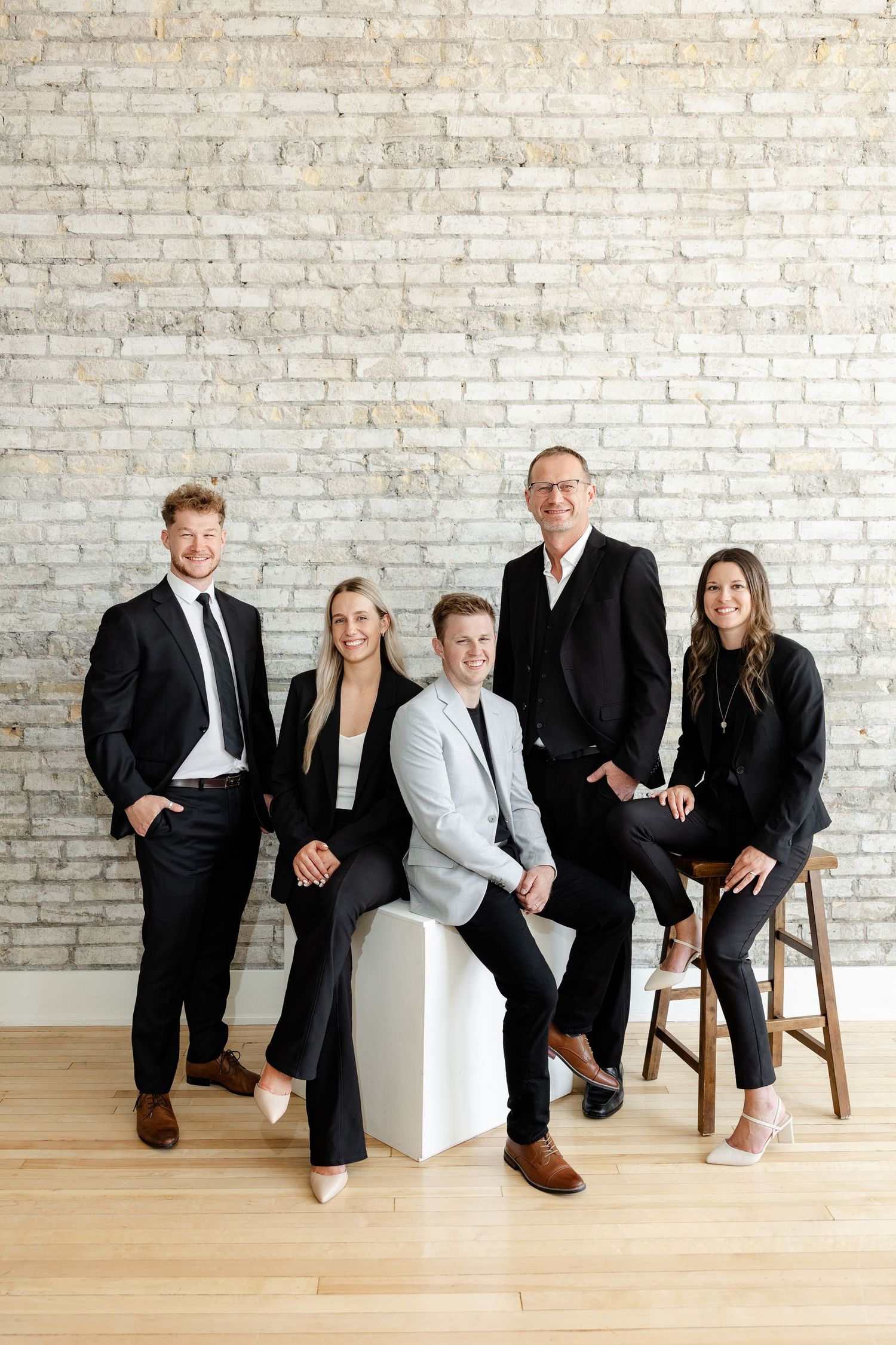 Group photo session with team members in business attire against white brick wall.
