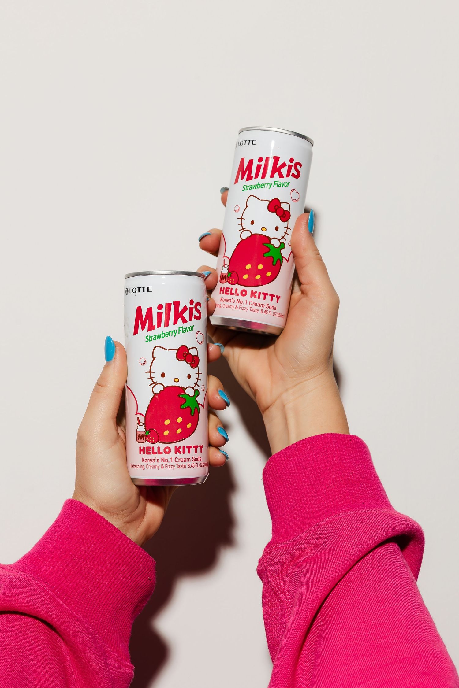 Hello Kitty branded drink cans held against white background.