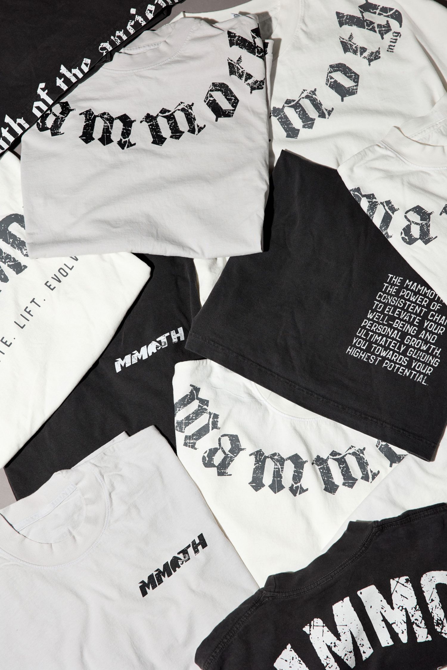 Collection of black and white t-shirts with gothic typography laid flat.