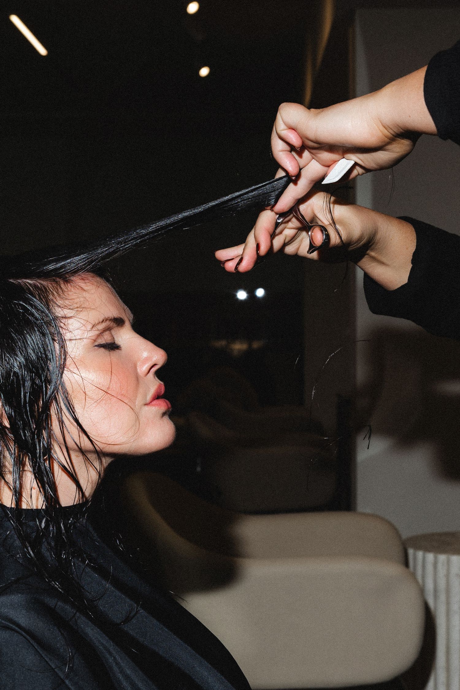 Side view of wet hair being styled in dark salon setting.
