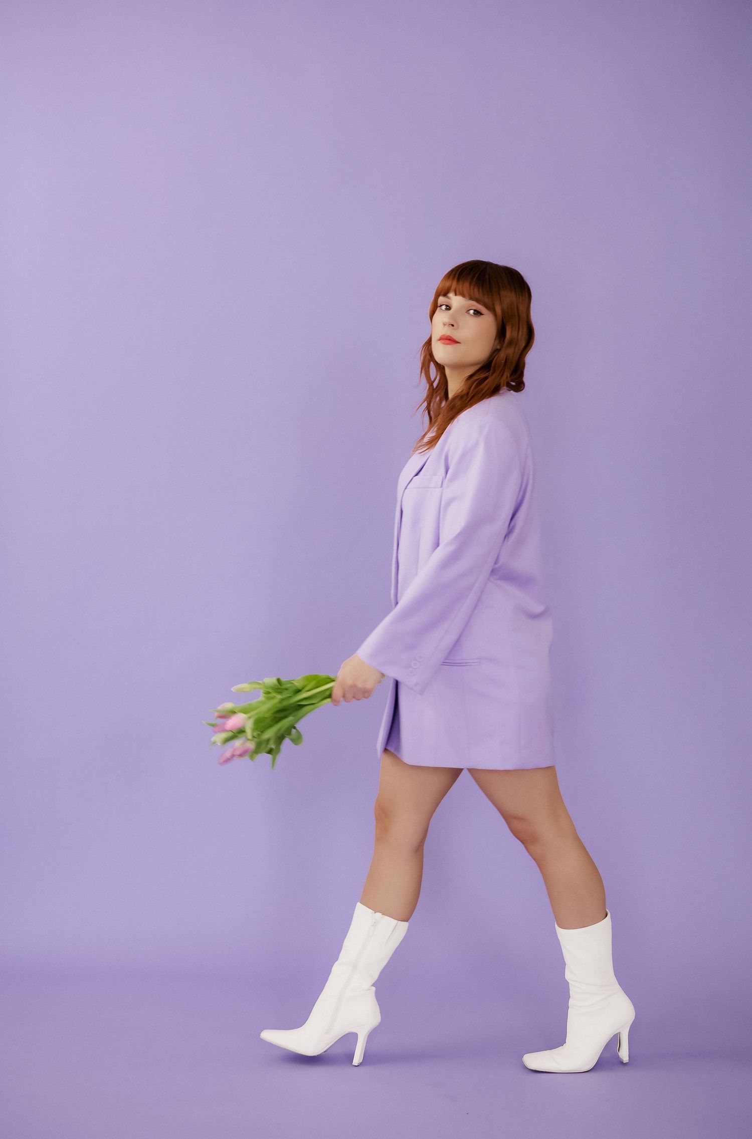 Dynamic poses with white boots and tulips against purple studio backdrop.