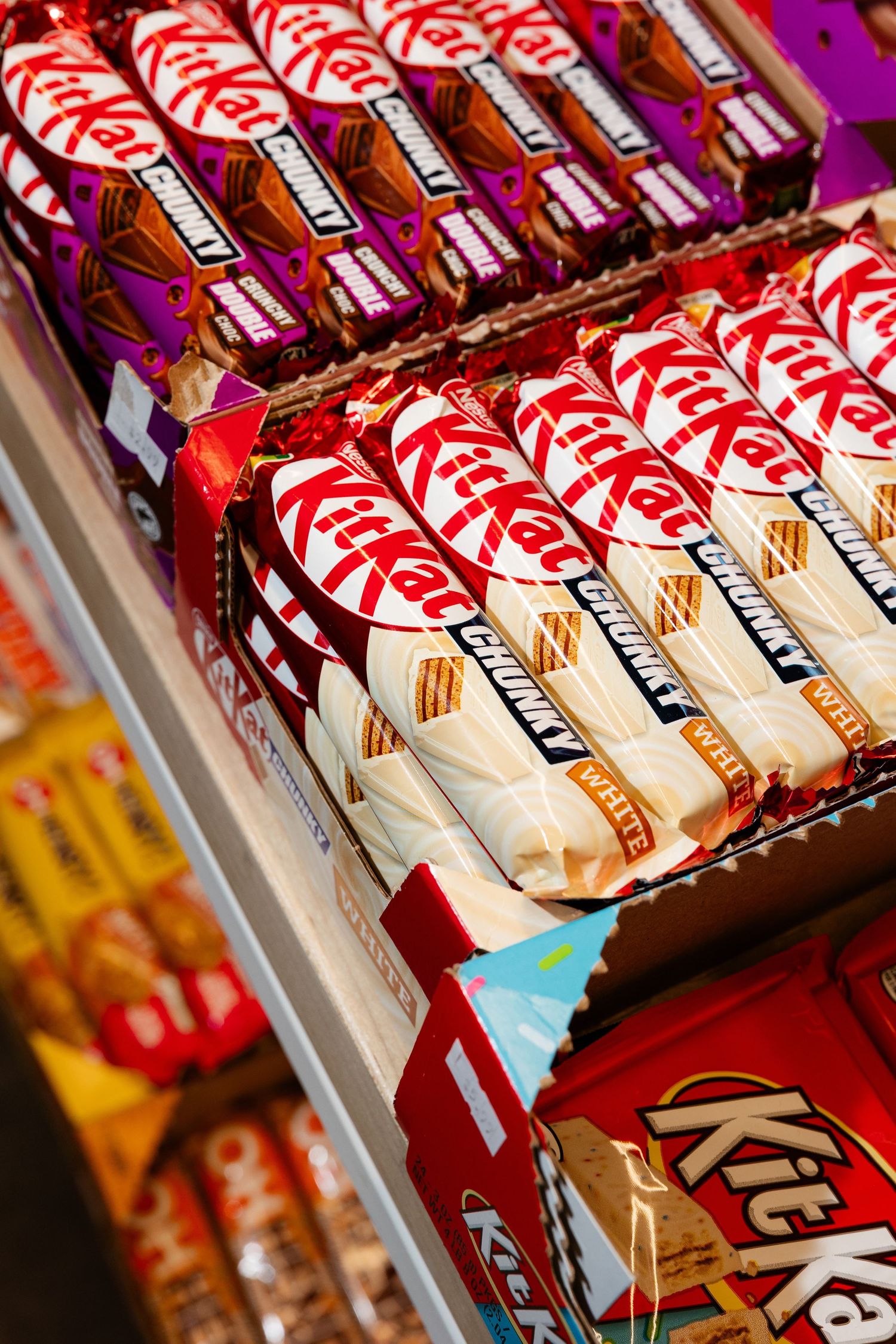 Display of red and white KitKat chocolate bars arranged on store shelves.