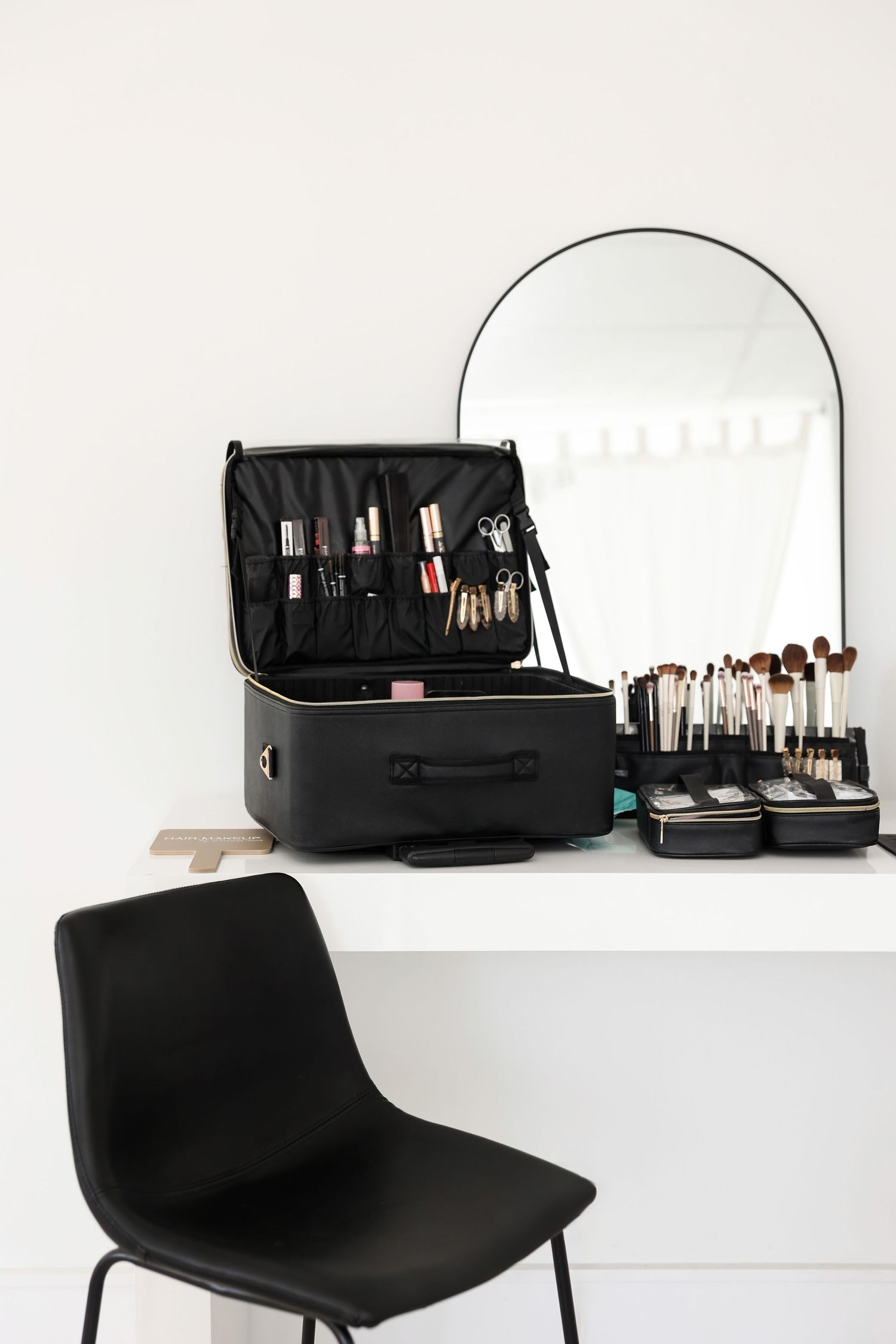 Black professional makeup cases and tools displayed on white modern furniture.