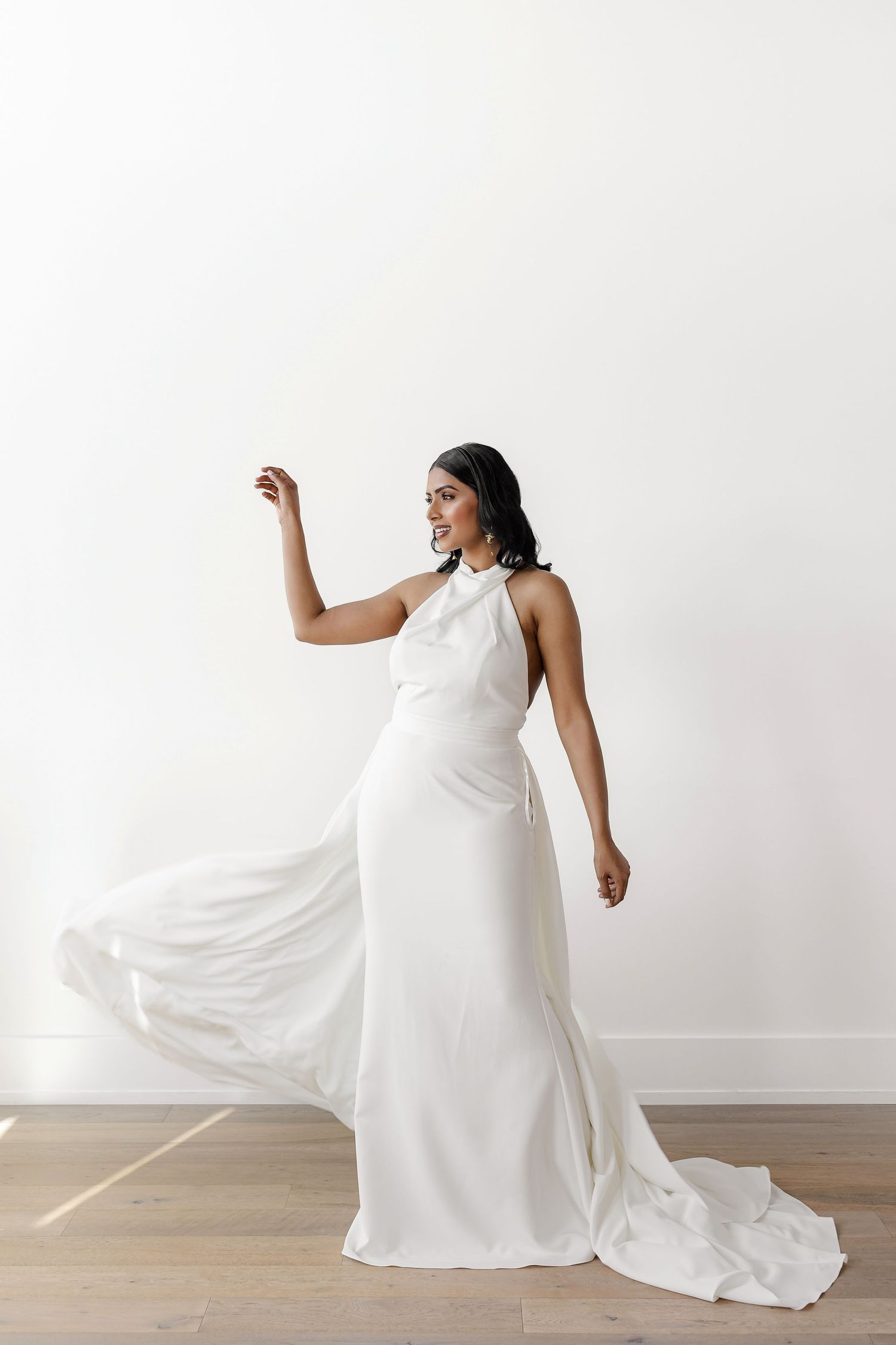 Flowing white wedding gown captured in dynamic movement against studio floor.