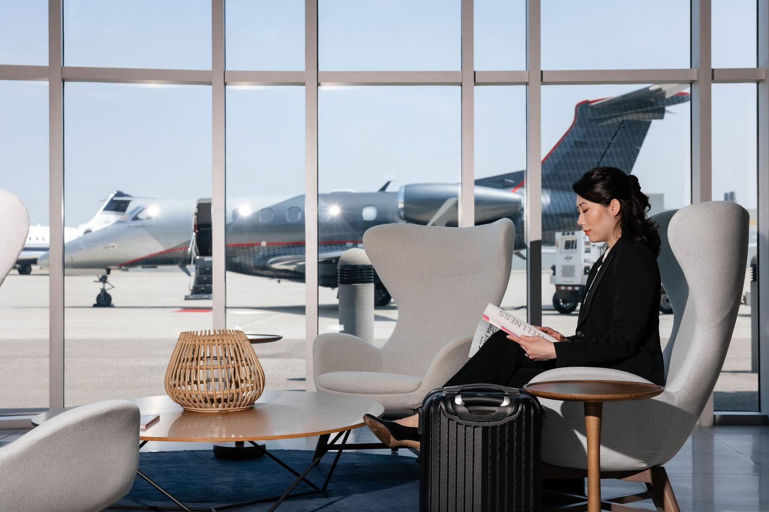 Airport lounge with panoramic windows overlooking runway and modern furnishings.