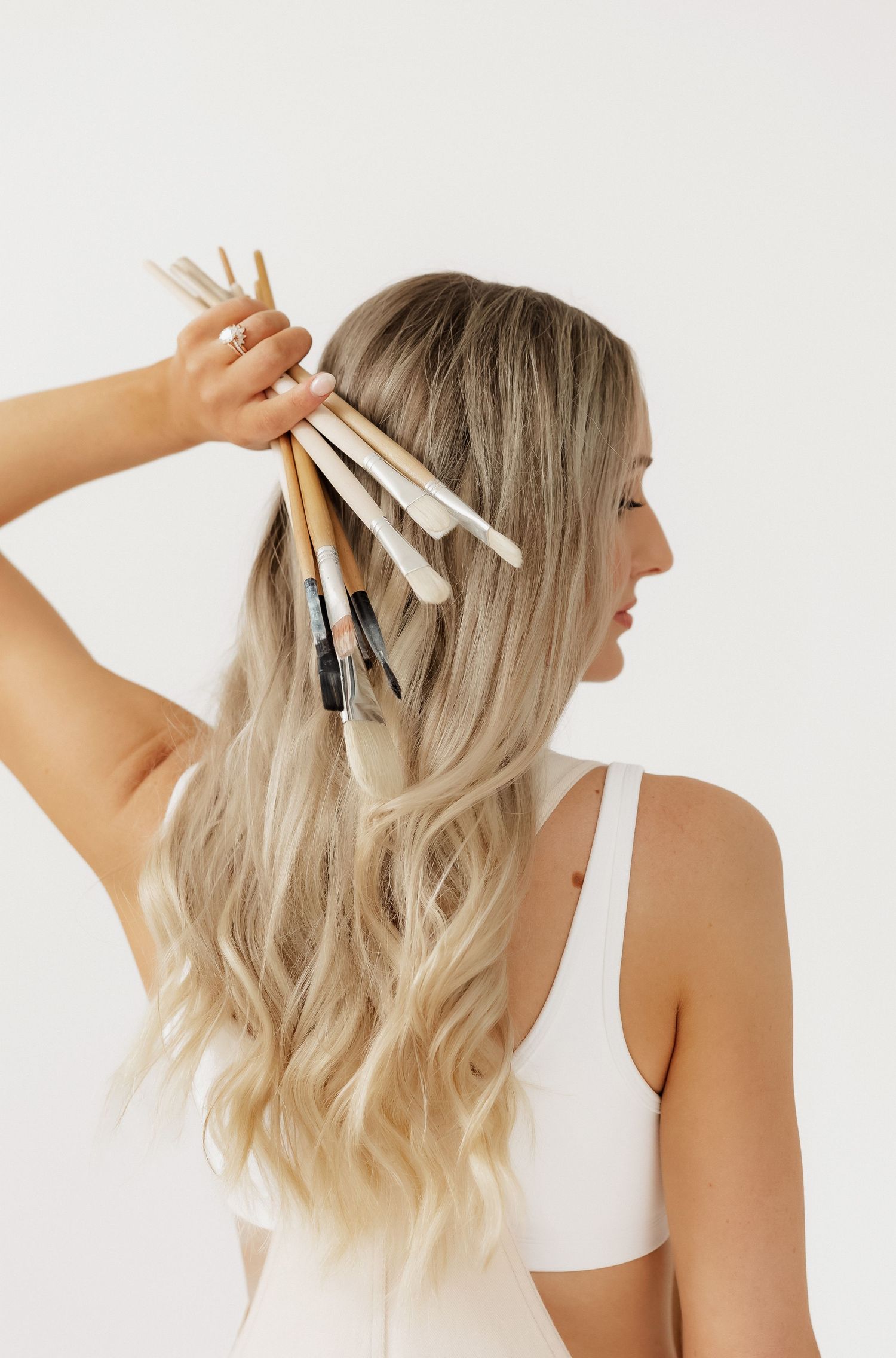 Back view of person with hair clips arranging hair against white background.