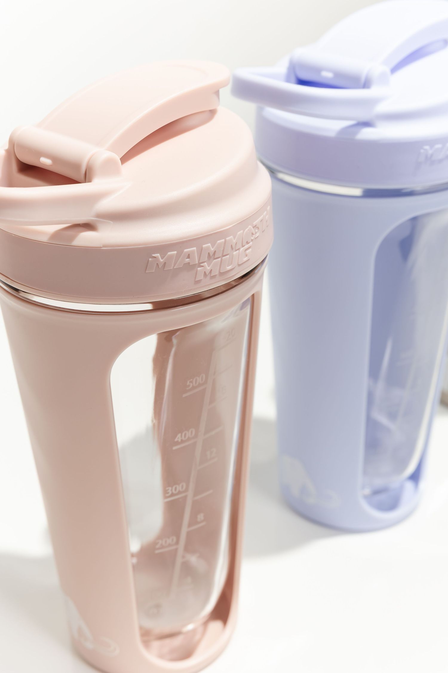 Pastel colored drink containers with measurement markings shown in soft lighting.