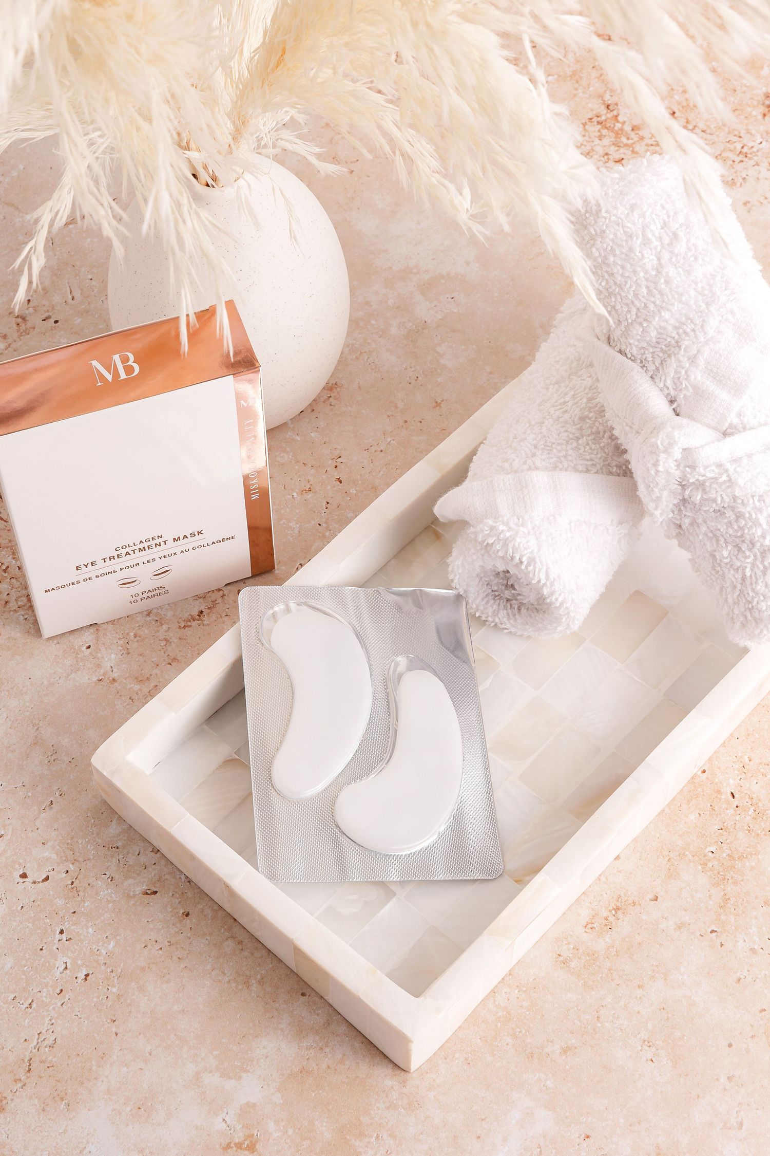 White eye treatment masks arranged on marble surface with elegant packaging.