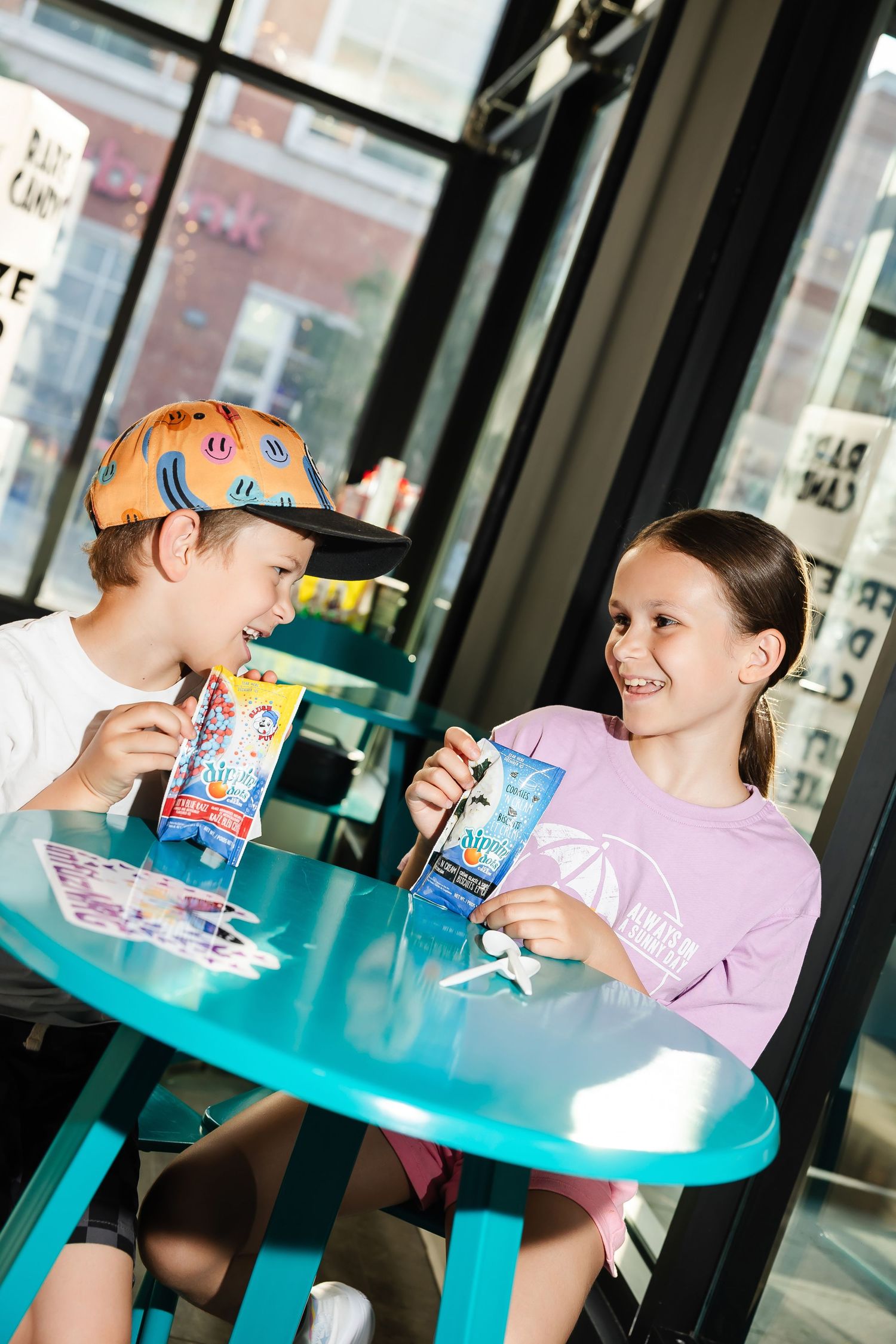 Children sharing snacks at a bright blue table near windows.