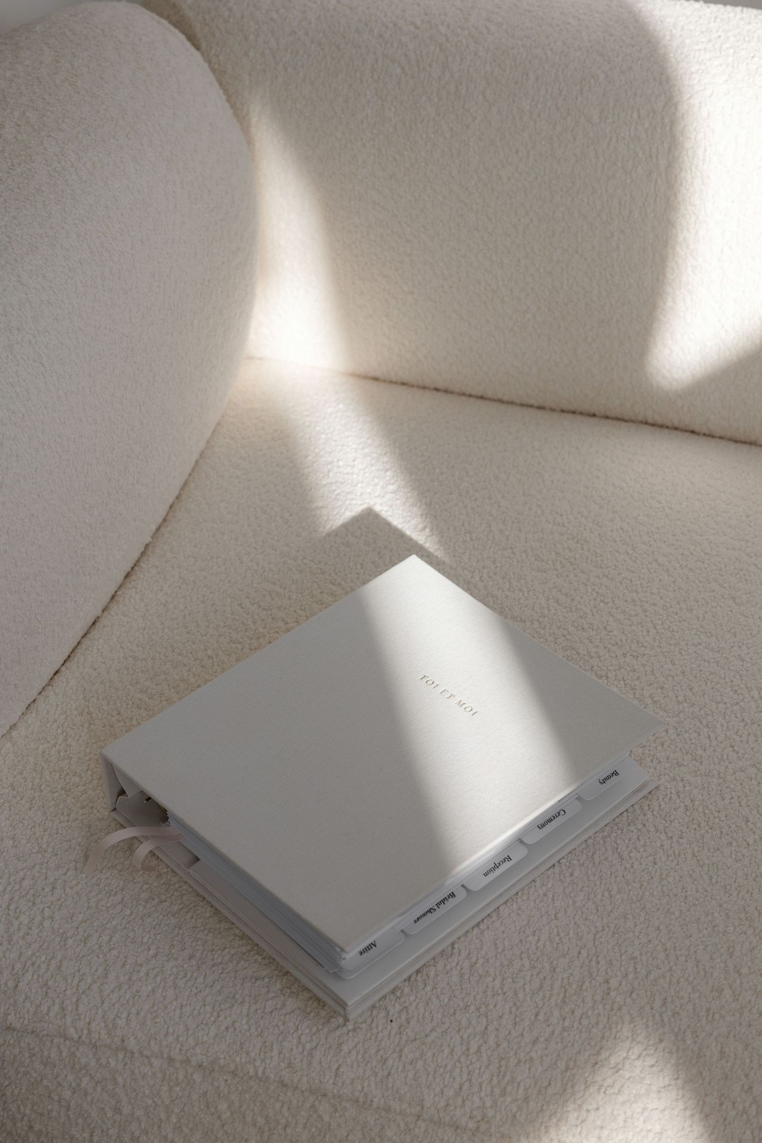 White spiral notebook lying on textured white surface with dramatic shadows.