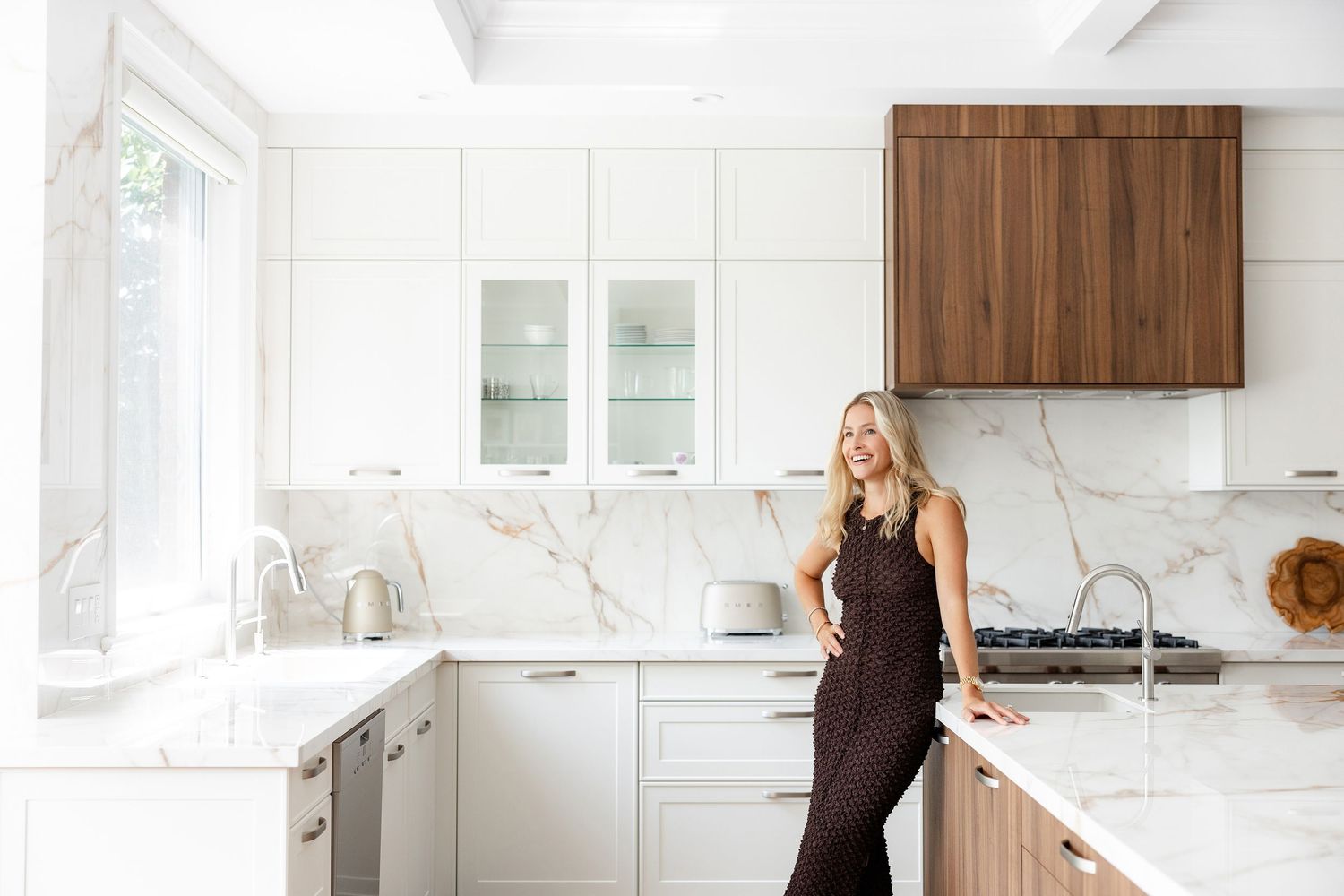 Modern white kitchen interior with marble countertops and wooden accents.