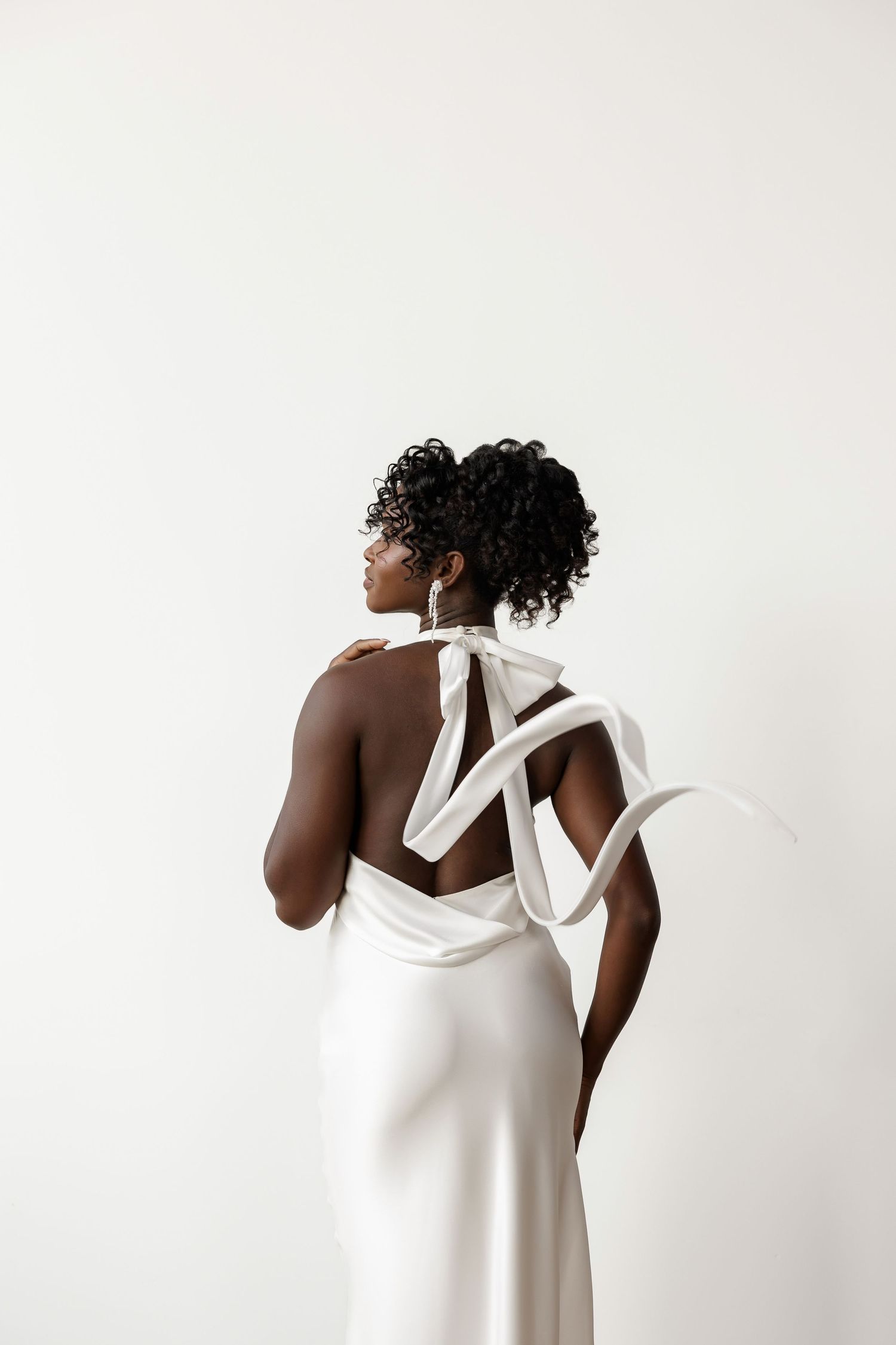 Modern white halter wedding dress showcased in minimalist studio setting.